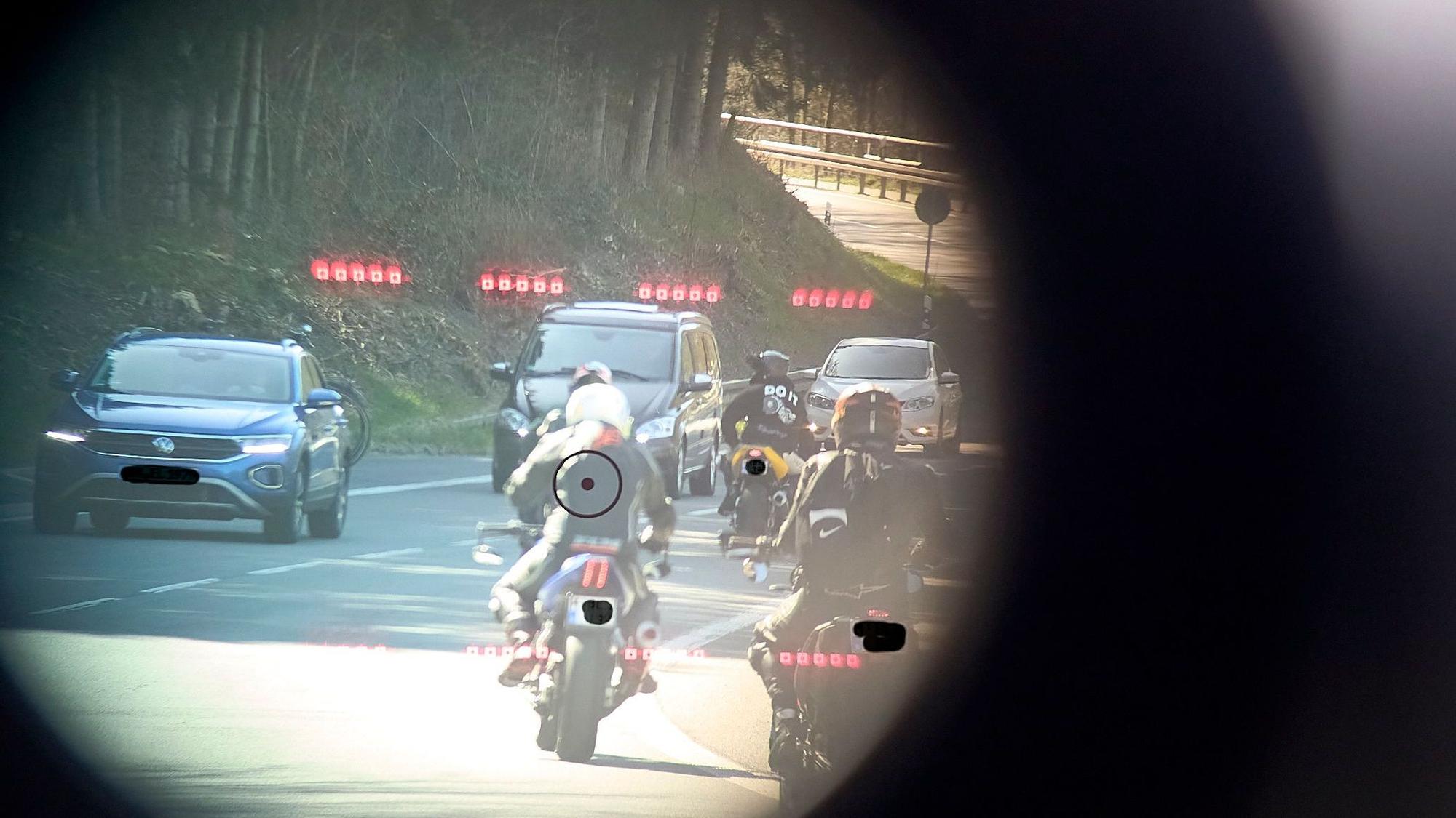 Das Symbolfoto ist durch ein Lasermessgerät der Polizei aufgenommen und zeigt den Blick auf eine von Motorrädern und Autos befahrene Straße.