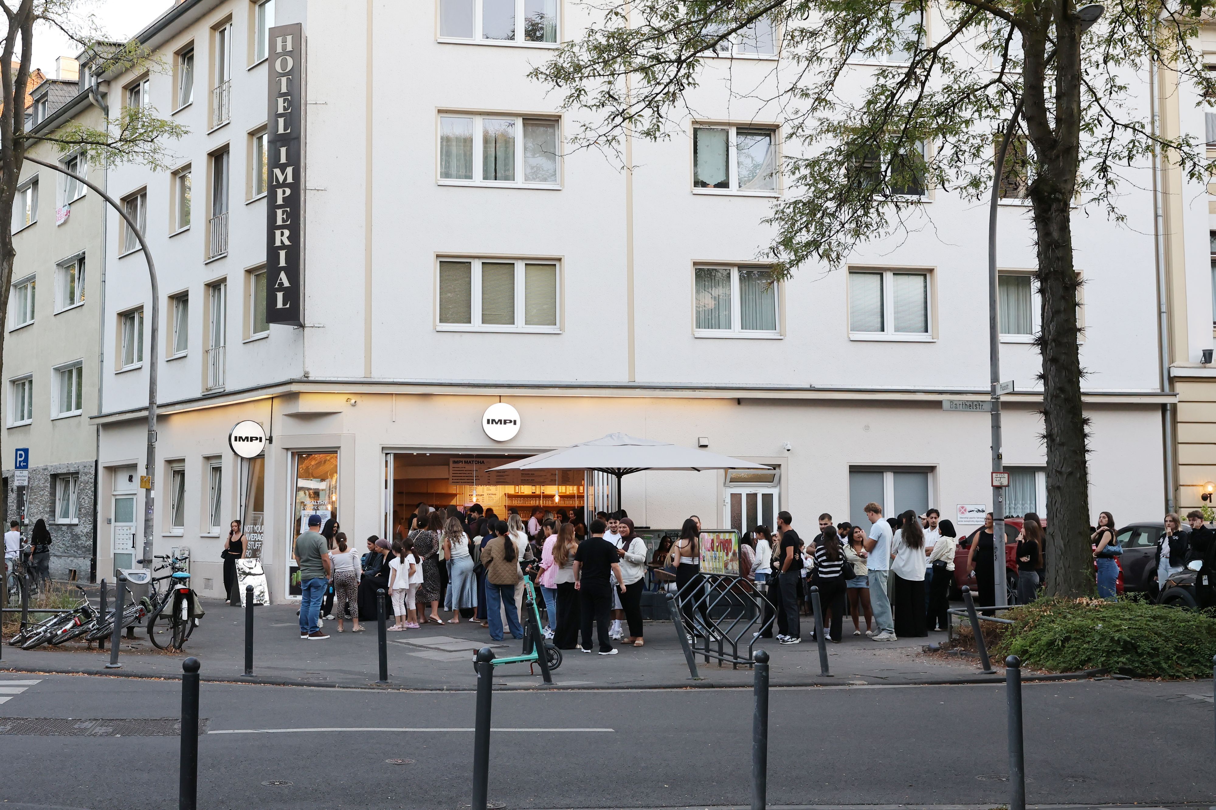 Eine lange Schlange junger Menschen wartet vor einem Eck-Café.