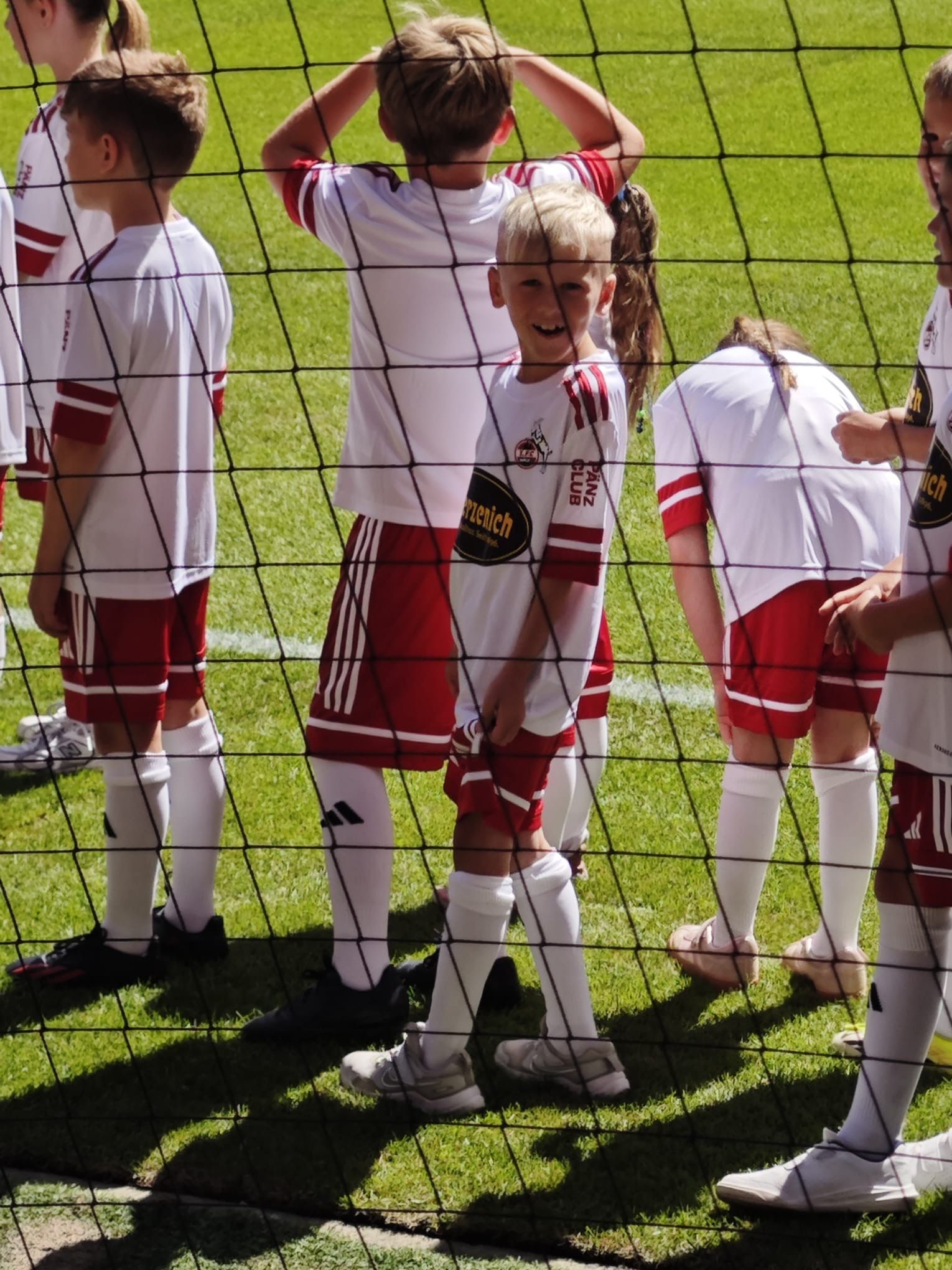 Elijah steht lächeln auf dem Platz neben den anderen Einlaufkindern.