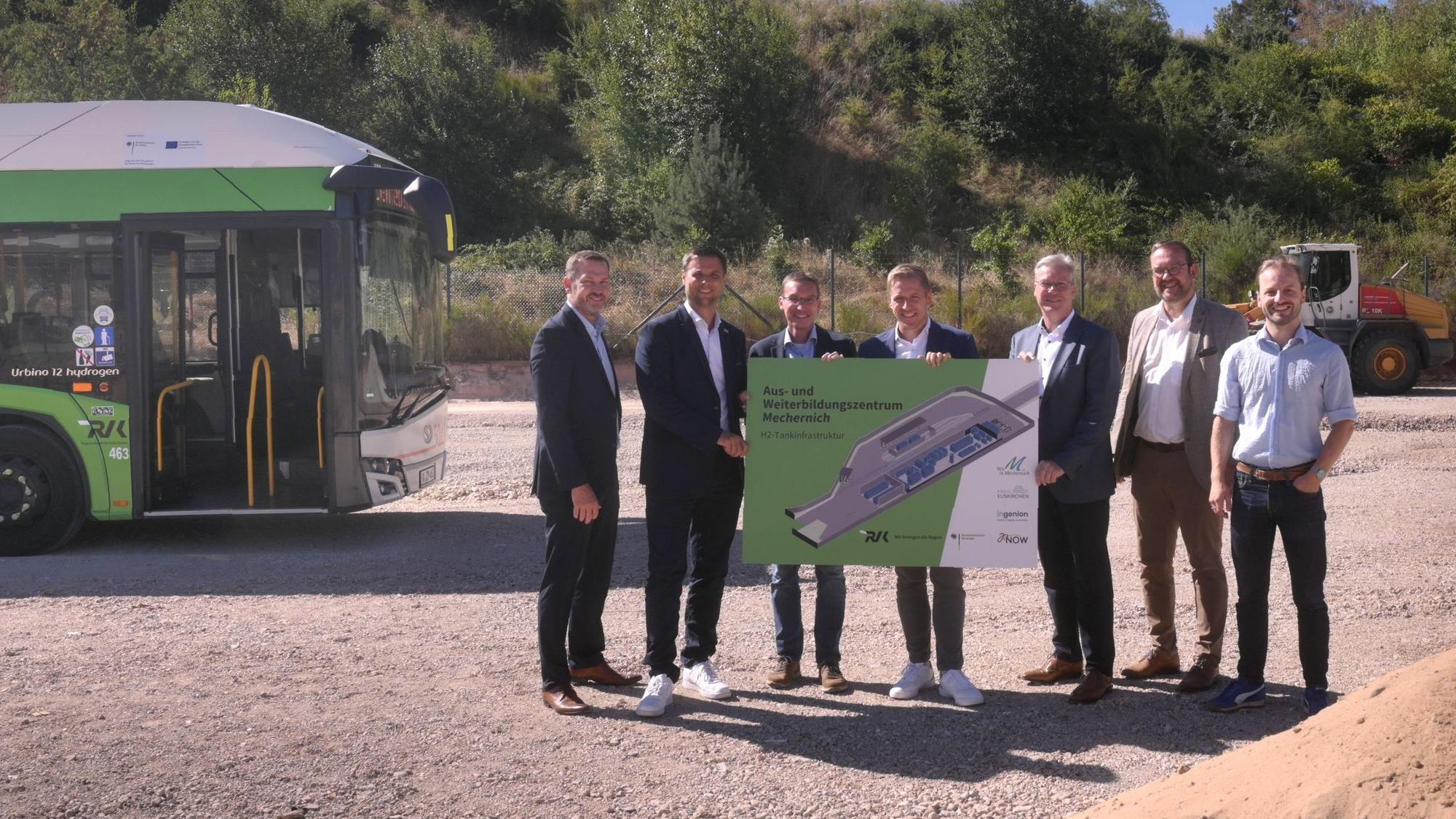Neben einem Bus stehen (v.l.) Heiko Iffland (Geschäftsführer Ingenion), Michael Fingel (Bürgermeister Stadt Mechernich), Dr. Marcel Frank (Geschäftsführer RVK), Markus Ramers (Landrat Kreis Euskirchen), Achim Blindert (Allg. Vertreter des Landrates Kreis Euskirchen), Thomas Hambach (Beigeordneter, Stadt Mechernich), Matthias Mohr (Anlagentechnik, RVK) und halten gemeinsam ein Plakat.