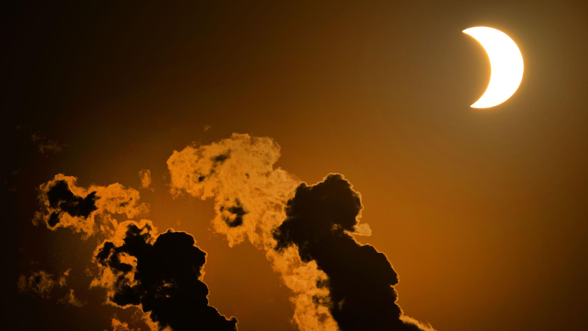 Die partielle Sonnenfinsternis ist am Himmel über dem Braunkohlekraftwerk Neurath in Pulheim bei Köln zu sehen.