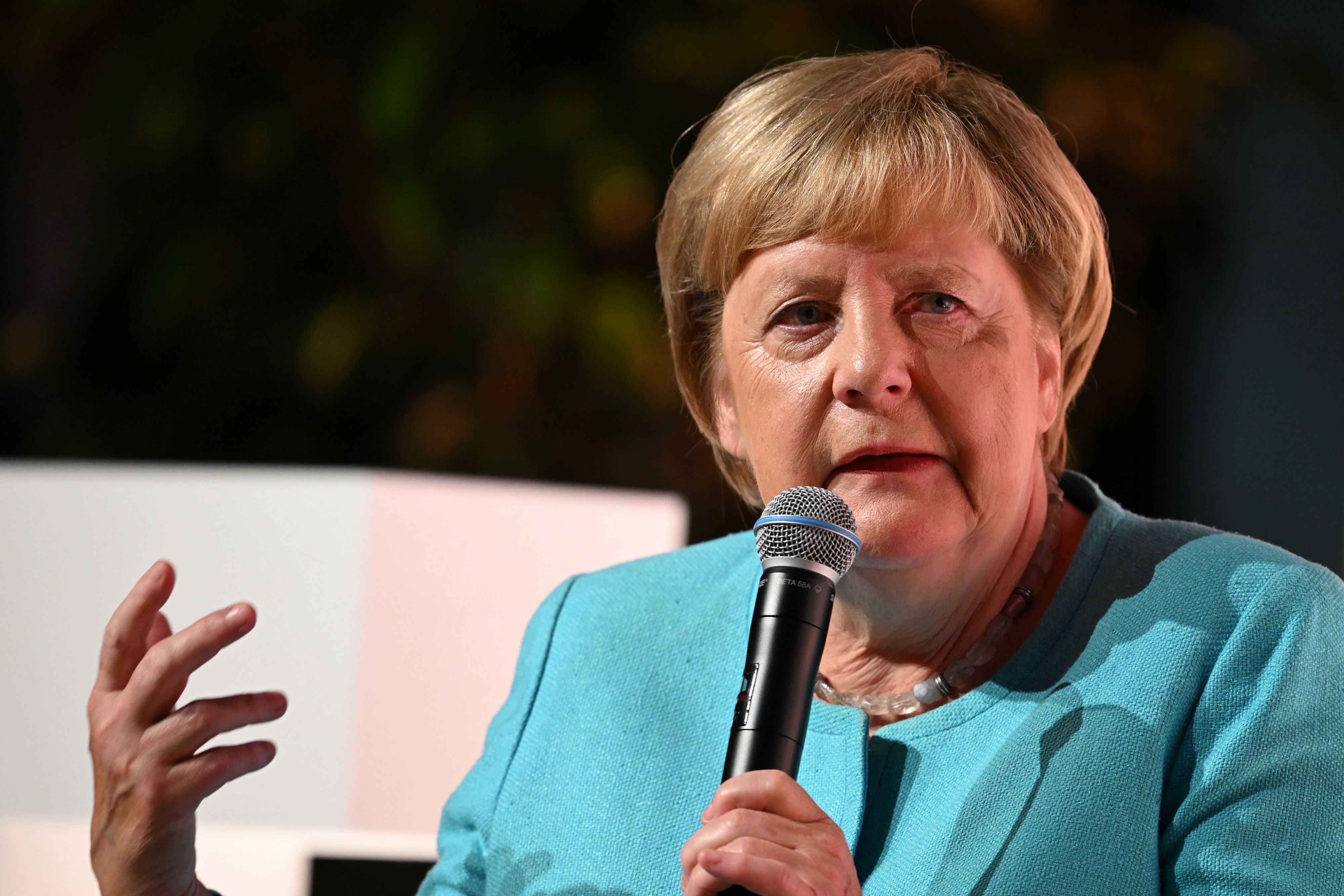 Angela Merkel (CDU) spricht bei einem Live-Interview mit Mikrofon in der Hand.