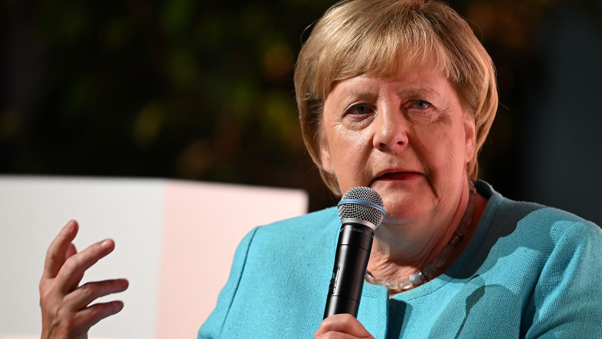 Angela Merkel (CDU) spricht bei einem Live-Interview mit Mikrofon in der Hand.