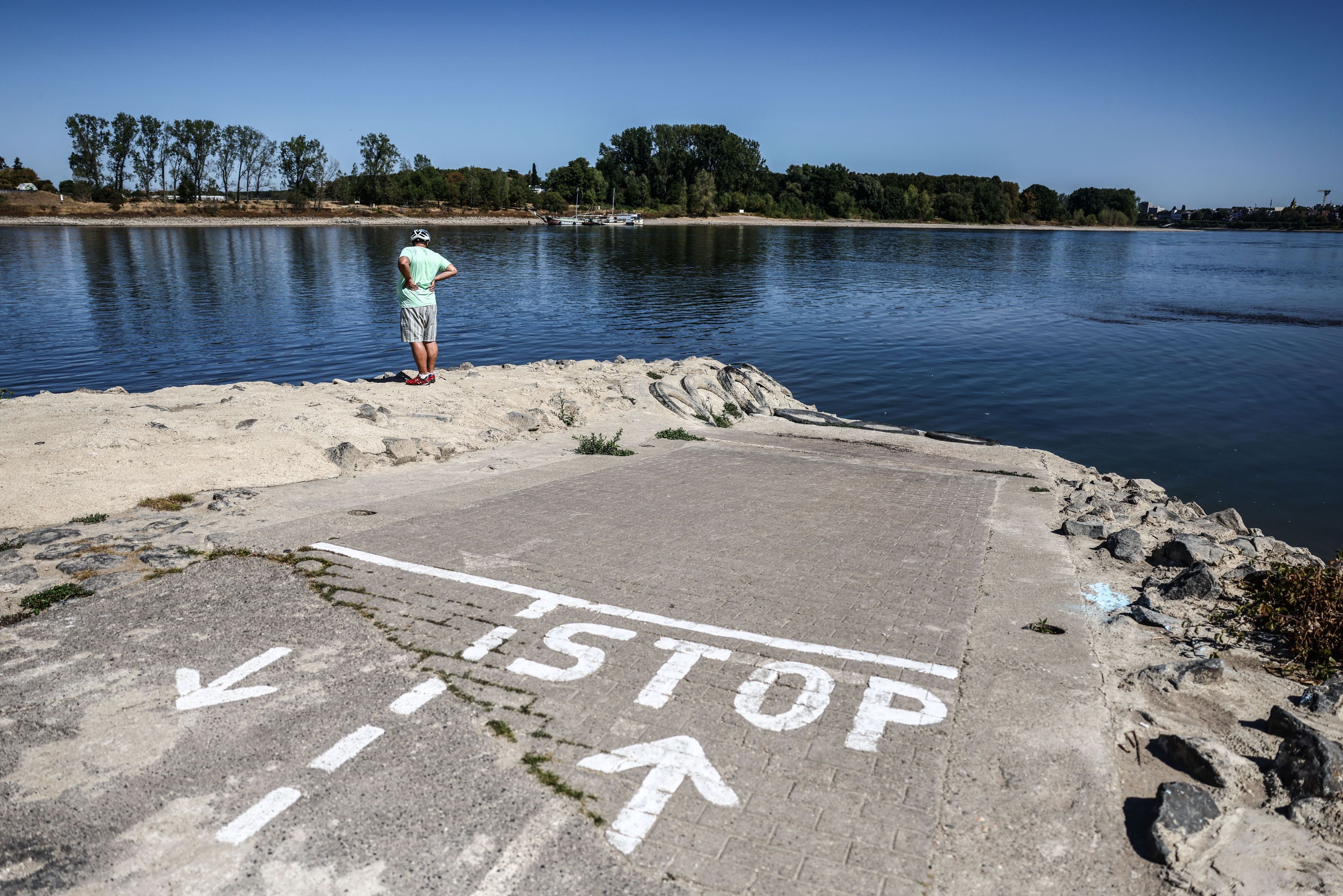 Ein Mann steht am Anleger einer Personenfähre bei Niedrigwasser am Kölner Rheinufer. Das Wetter bleibt zunächst trocken und heiß.