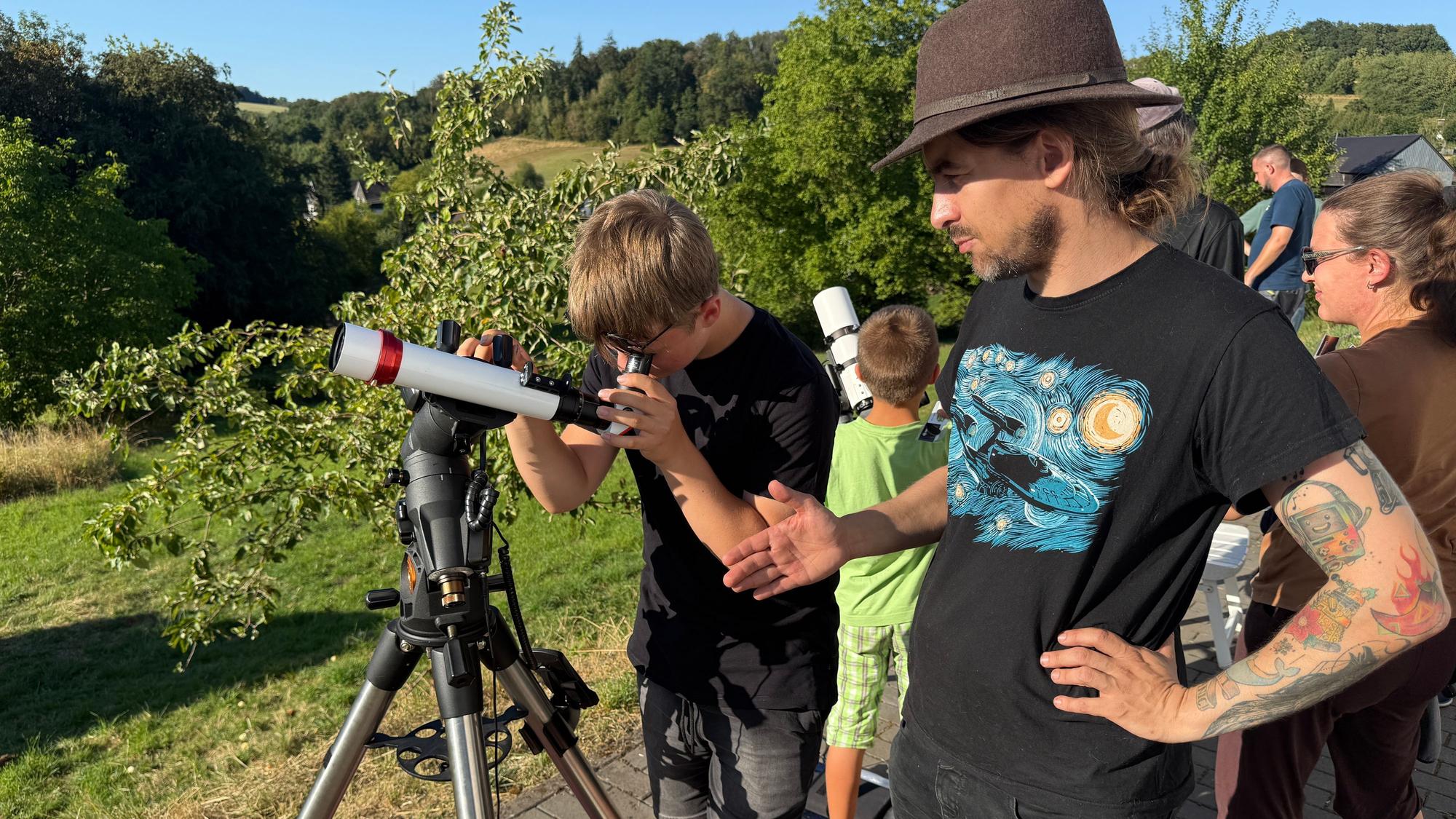 Ein Junge und ein Mann an einem Teleskop.