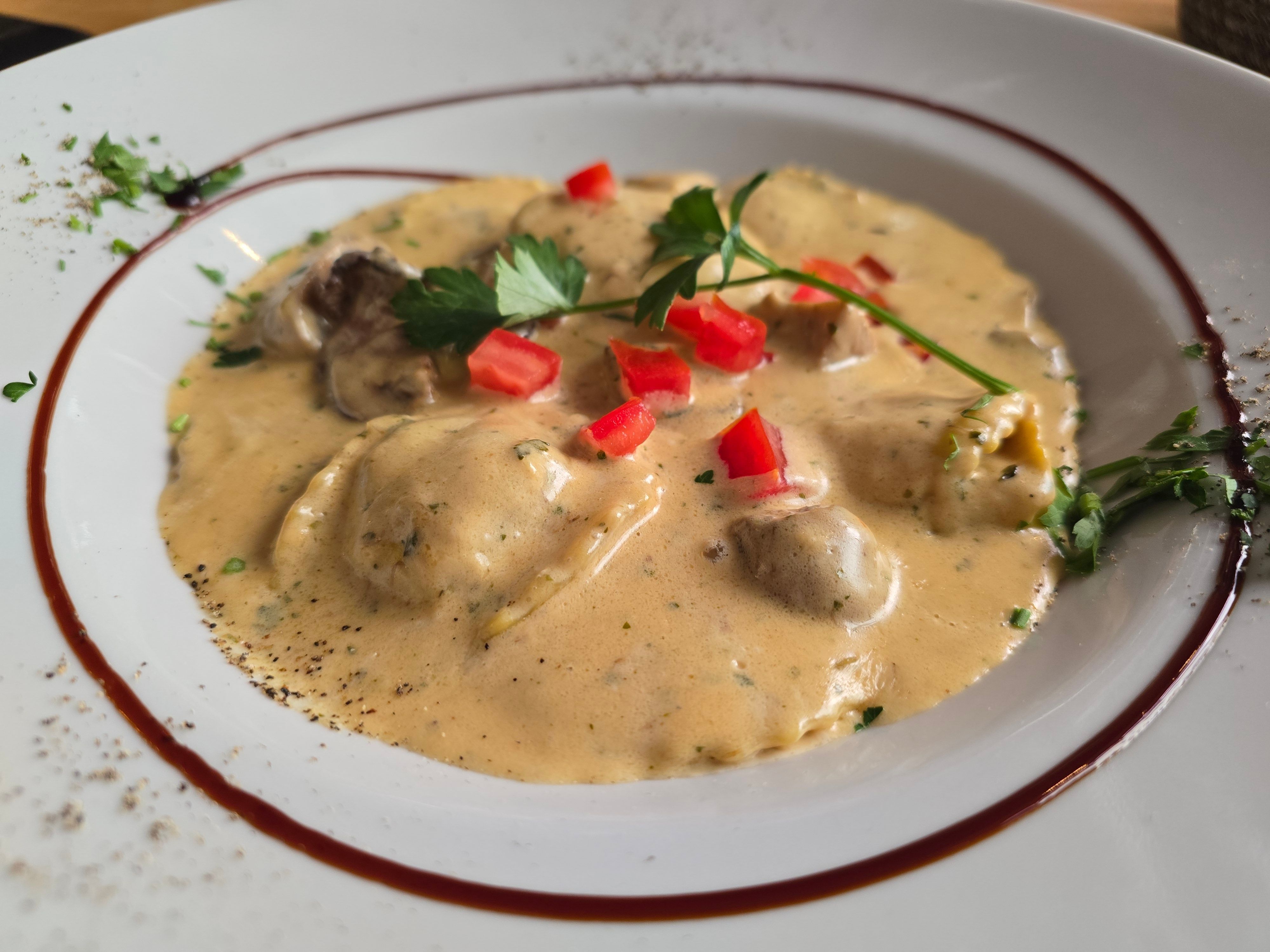 Ein Teller mit Pasta in Waldpilz-Sauce garniert mit etwas Grün.