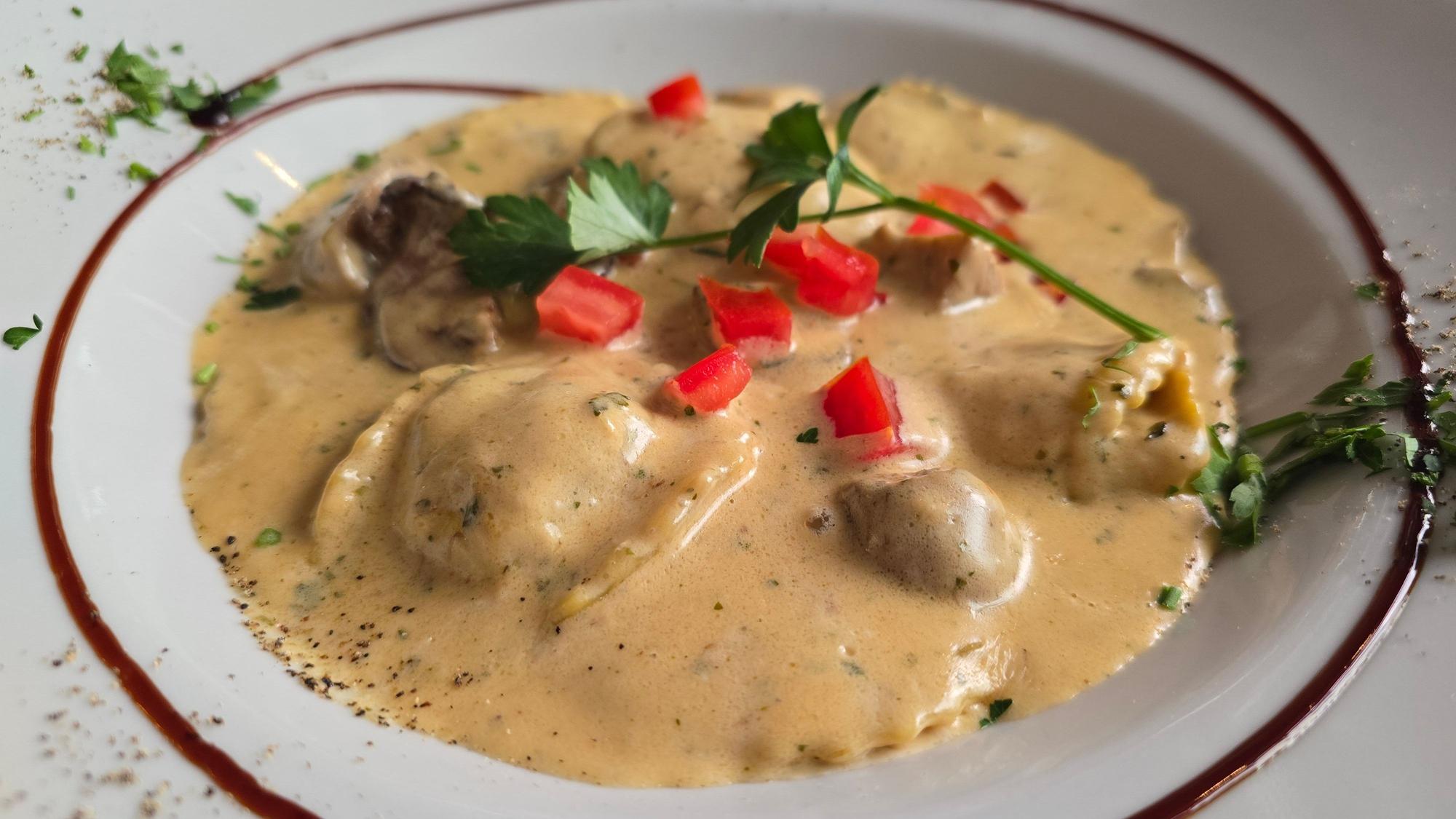 Ein Teller mit Pasta in Waldpilz-Sauce garniert mit etwas Grün.