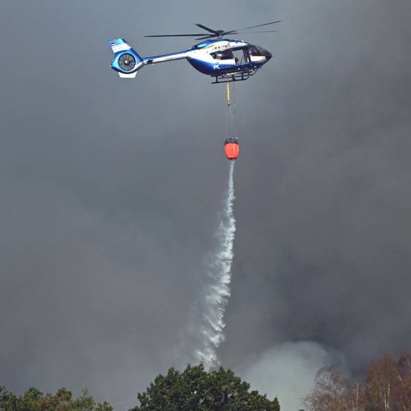 Ein Polizeihubschrauber mit Löschwasser-Außenlastbehälter unterstützt die Löscharbeiten beim Waldbrand im Hürtgenwald.