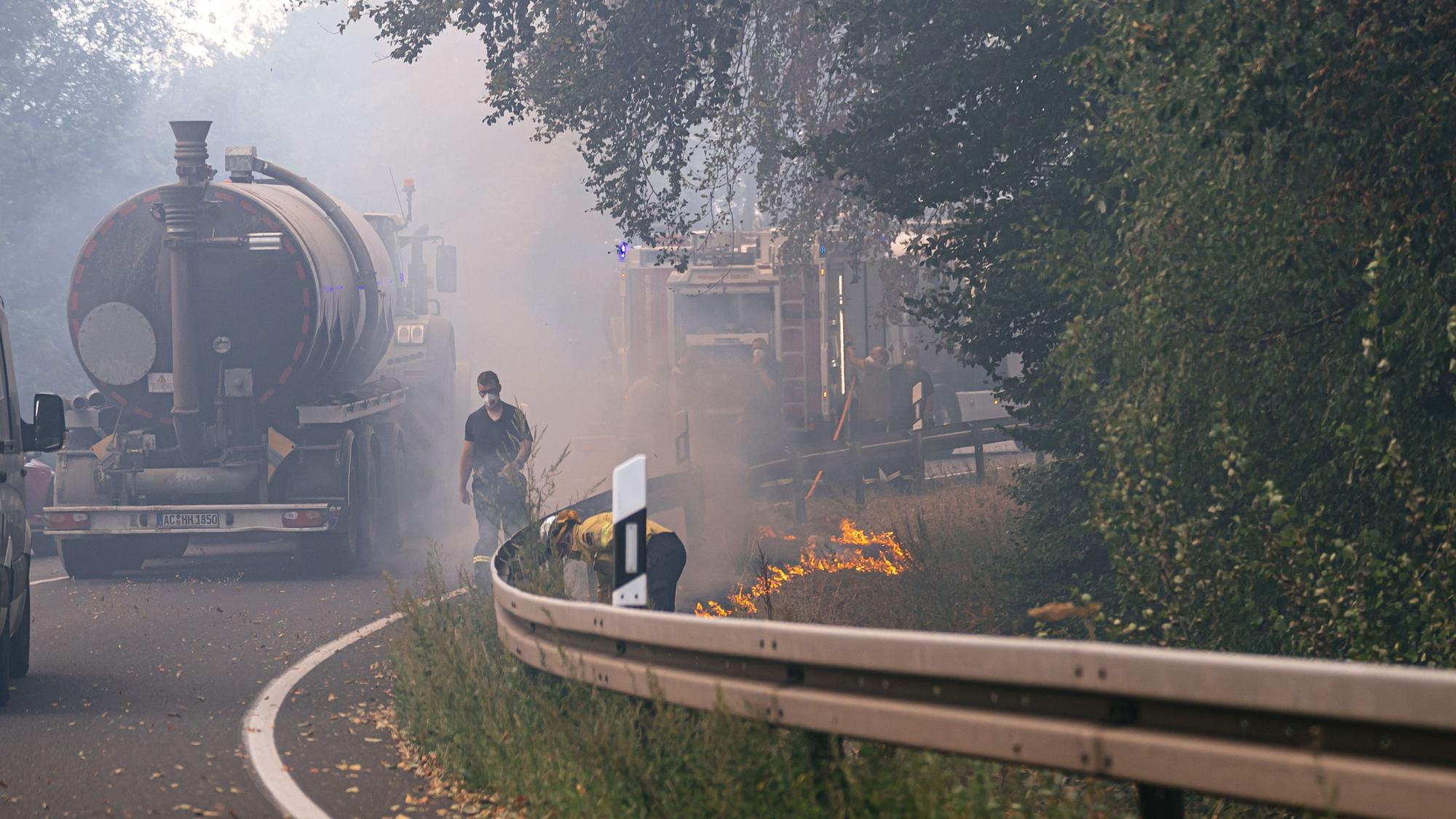 Waldbrand im Hürtgenwald. Am Straßenrand legen Einsatzkräfte ein sogenanntes Gegenfeuer und setzen Vegetation kontrolliert in Brand. So soll dem eigentlichen Feuer die Nahrung entzogen werden, wenn es die Stelle erreicht.