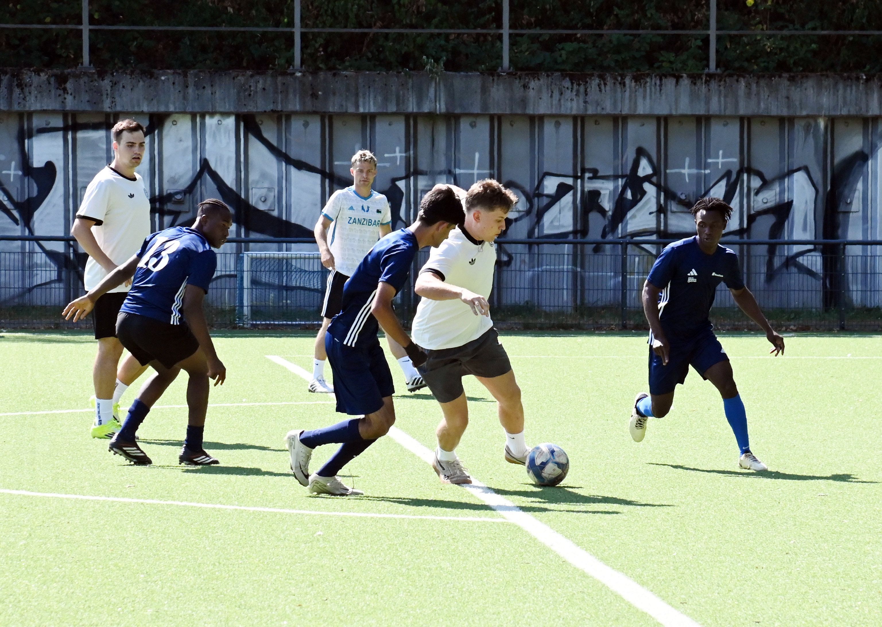 Zwei der zwölf Mannschaften duellieren sich im Gruppenspiel im Stadion des ESV Olympia in Nippes. Im Bild sind sechs Spieler rund um den Ball.