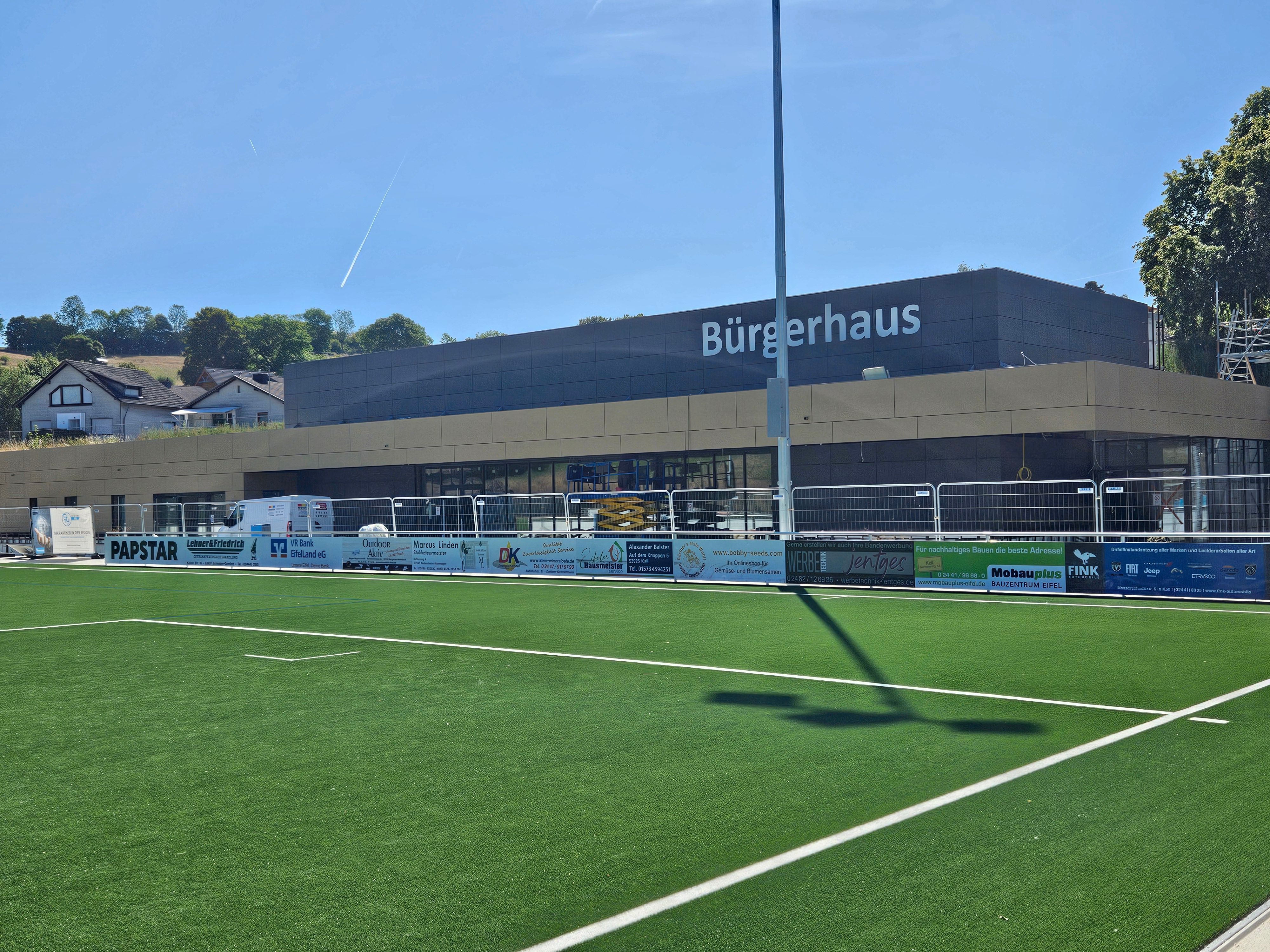 Blick auf einen Teil des Sportplatzes und das im Bau befindliche Bürgerhaus.