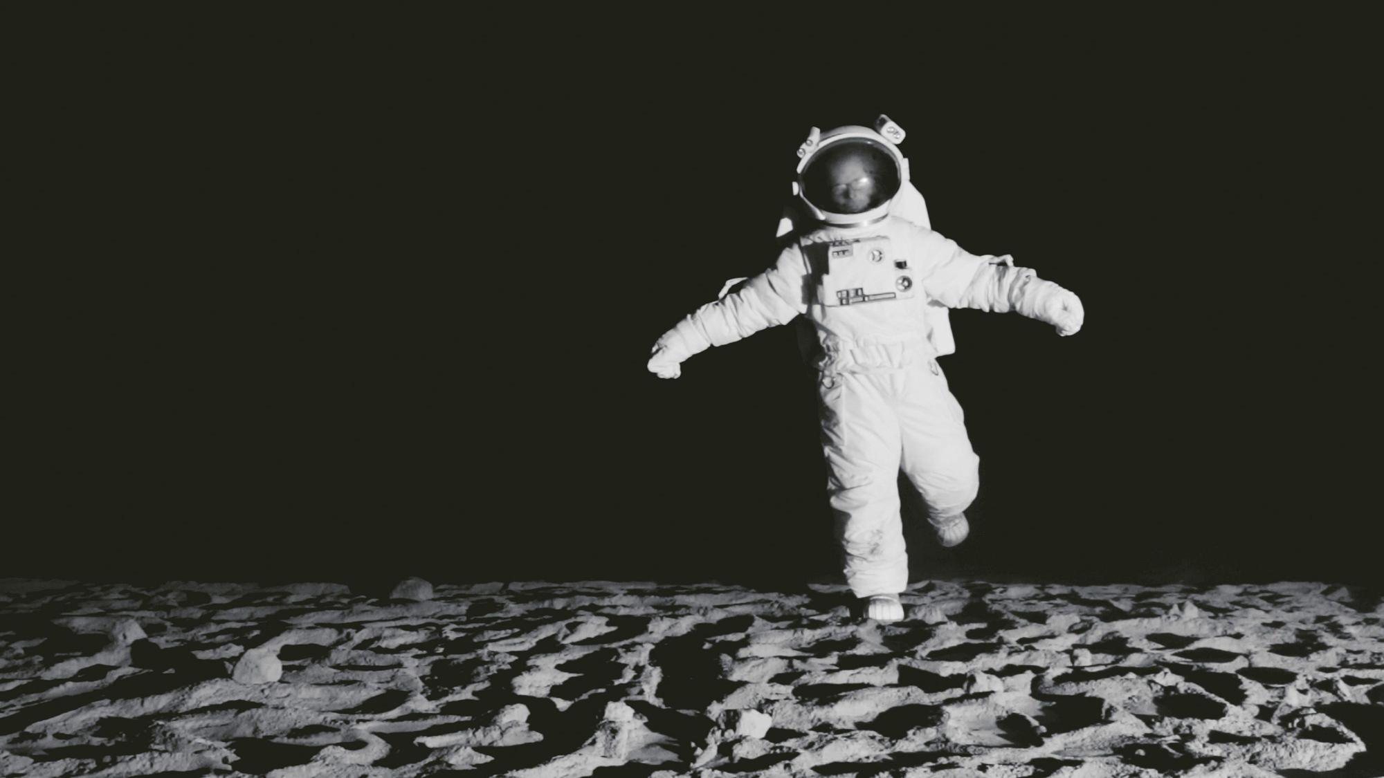 Ein Astronaut steht gelangweilt auf dem Mond.