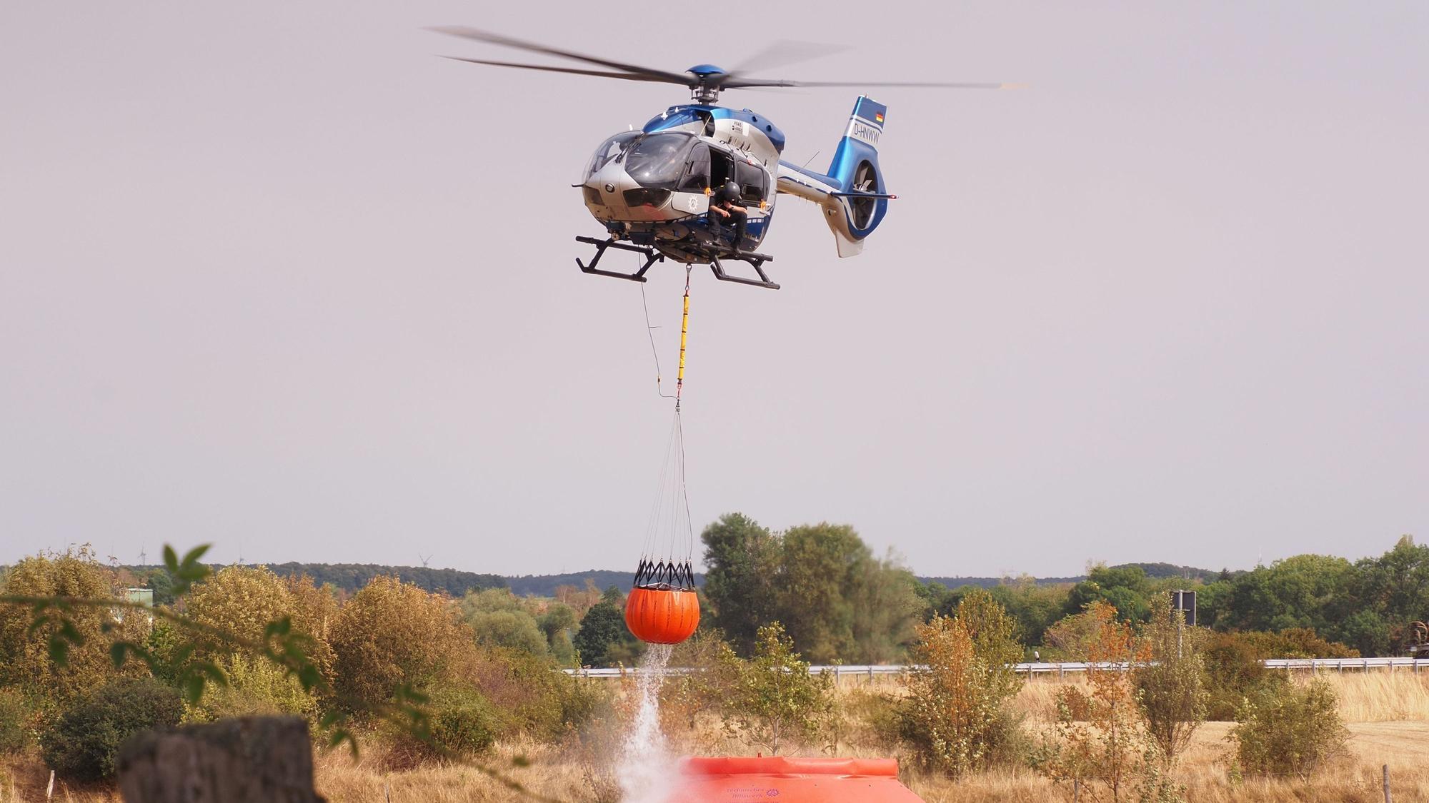 Ein Hubschrauber nimmt nahe der Ortschaft Gey Löschwasser auf.
