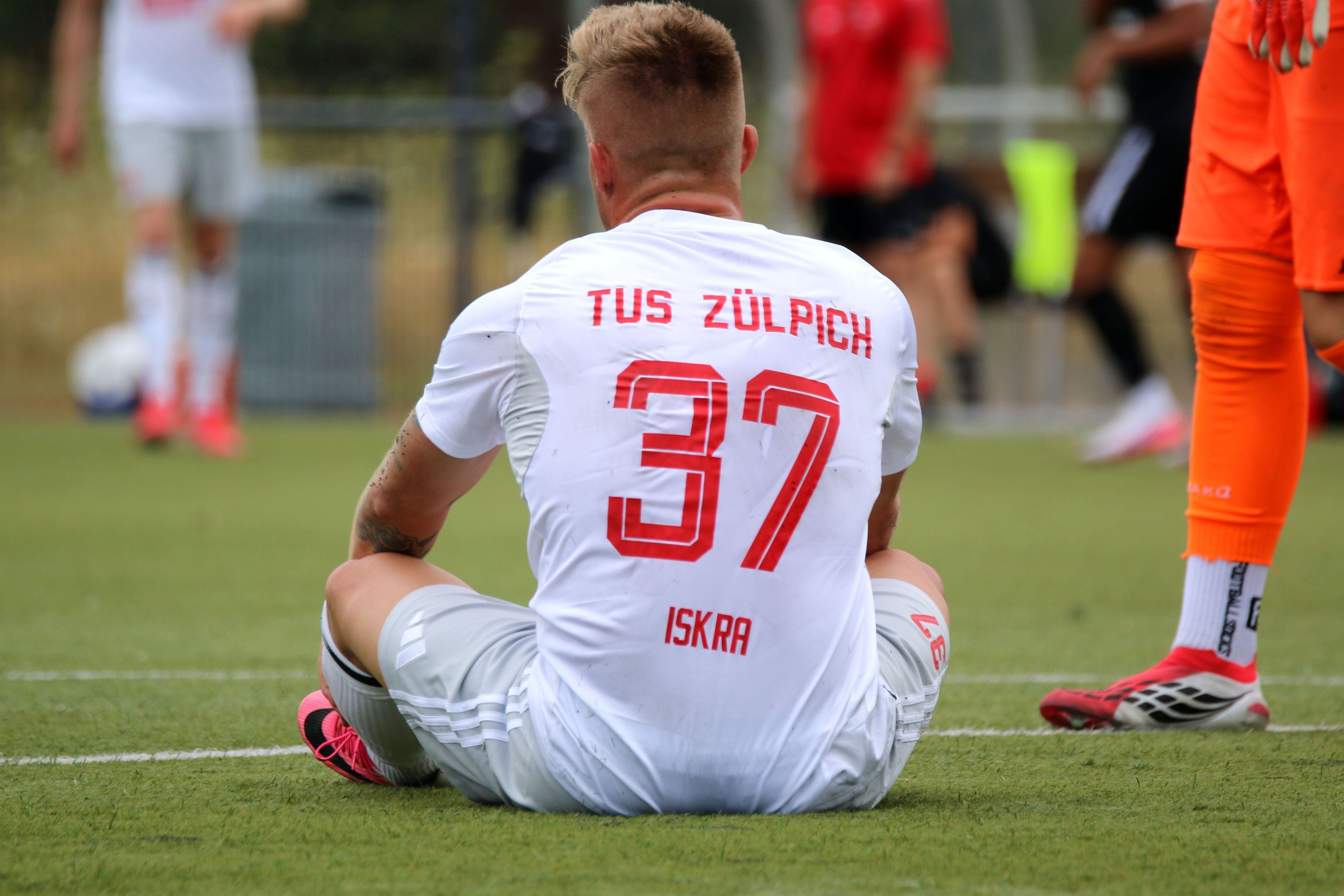 Marvin Iskra sitzt auf dem Boden. Auf dem Trikot steht nun nicht nur die Rückennummer, sondern auch sein Name.