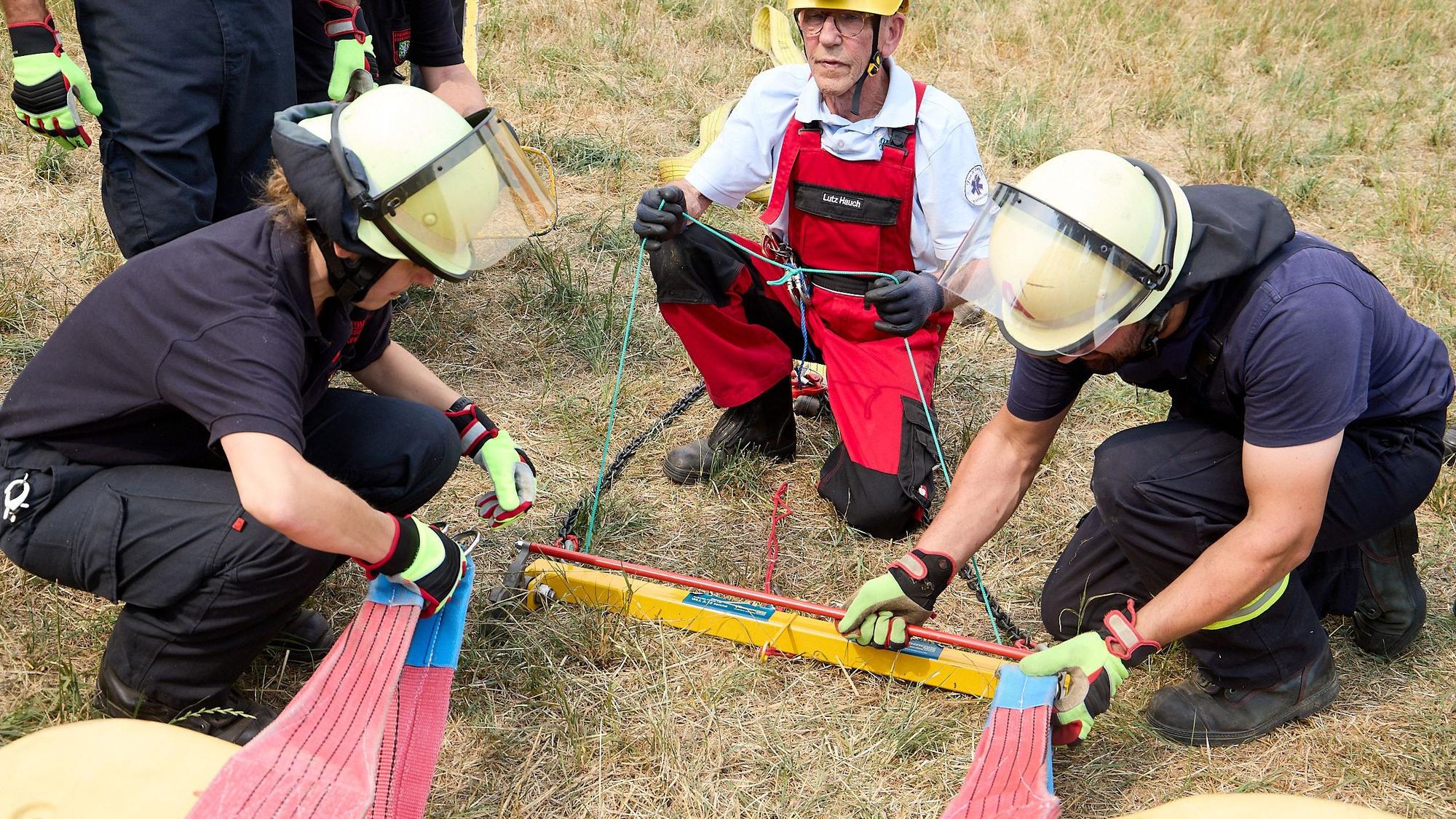 Zwei Feuerwehrleute befestgen ein Geschirr am Pferd.