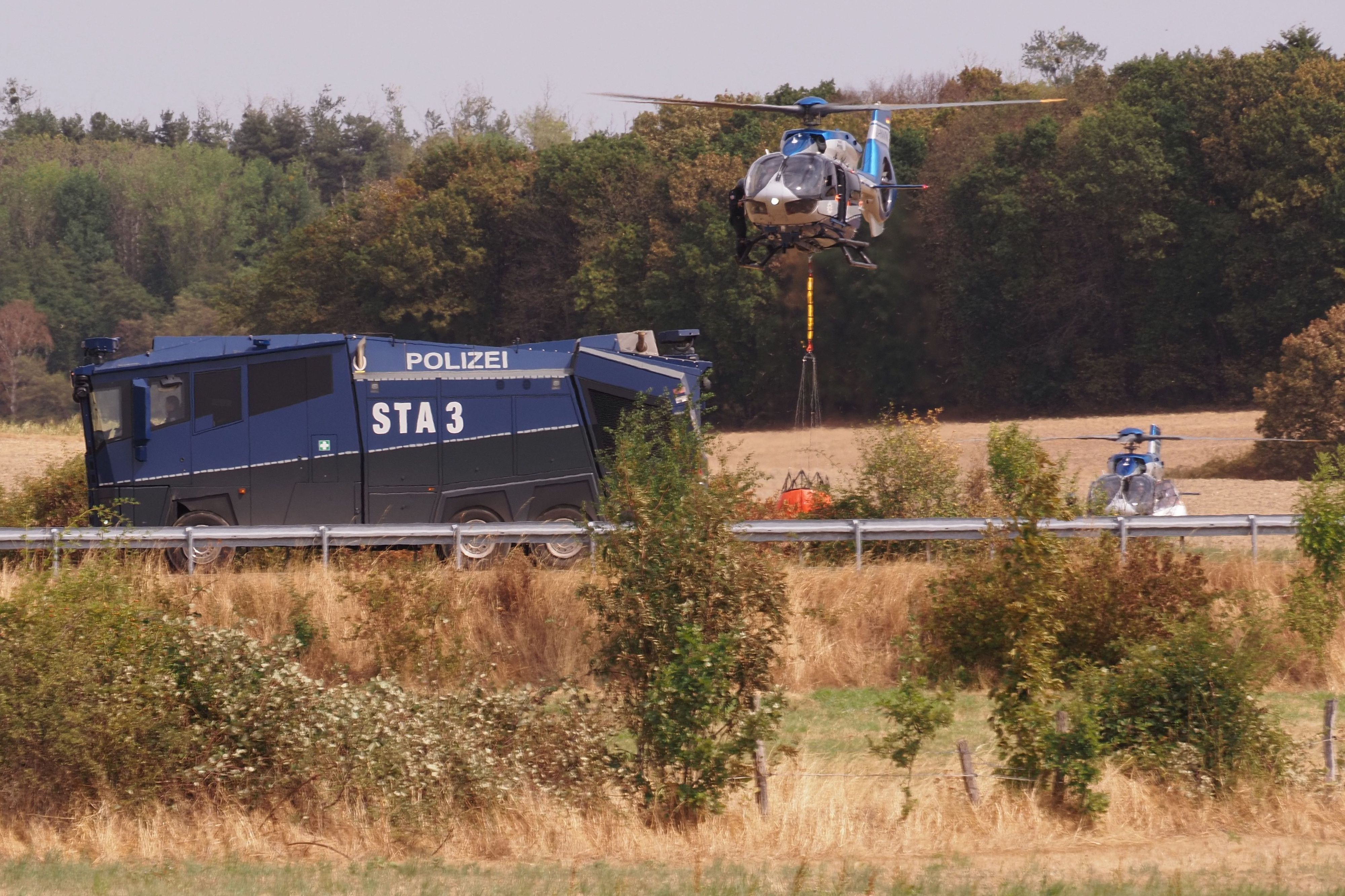 Löschhubschrauber und Wasserwerfer der Polizei nahe der Ortschaft Gey.