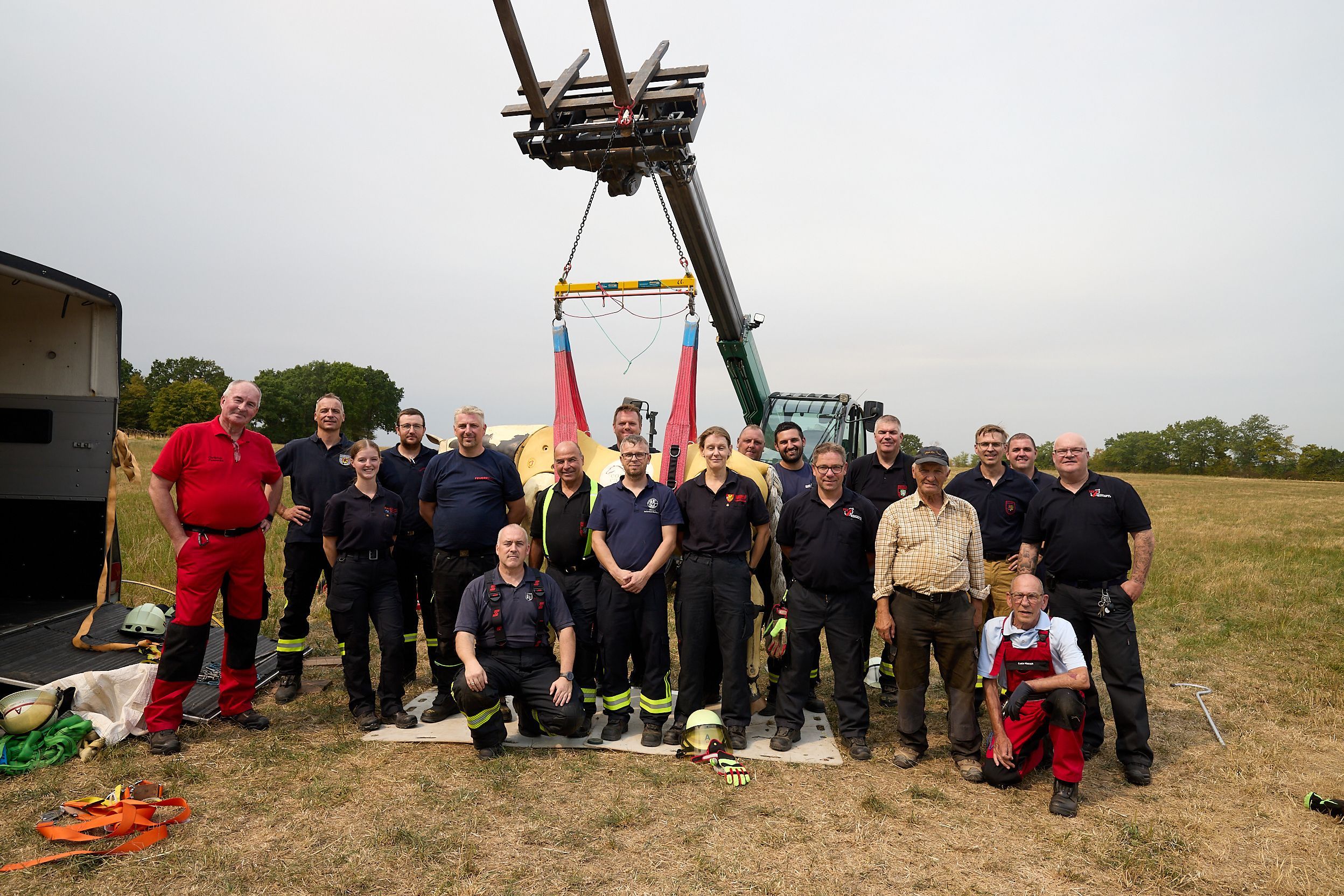 Feuerwehrleute stehen zu einem Gruppenbild mit hängendem Pferd zusammen.