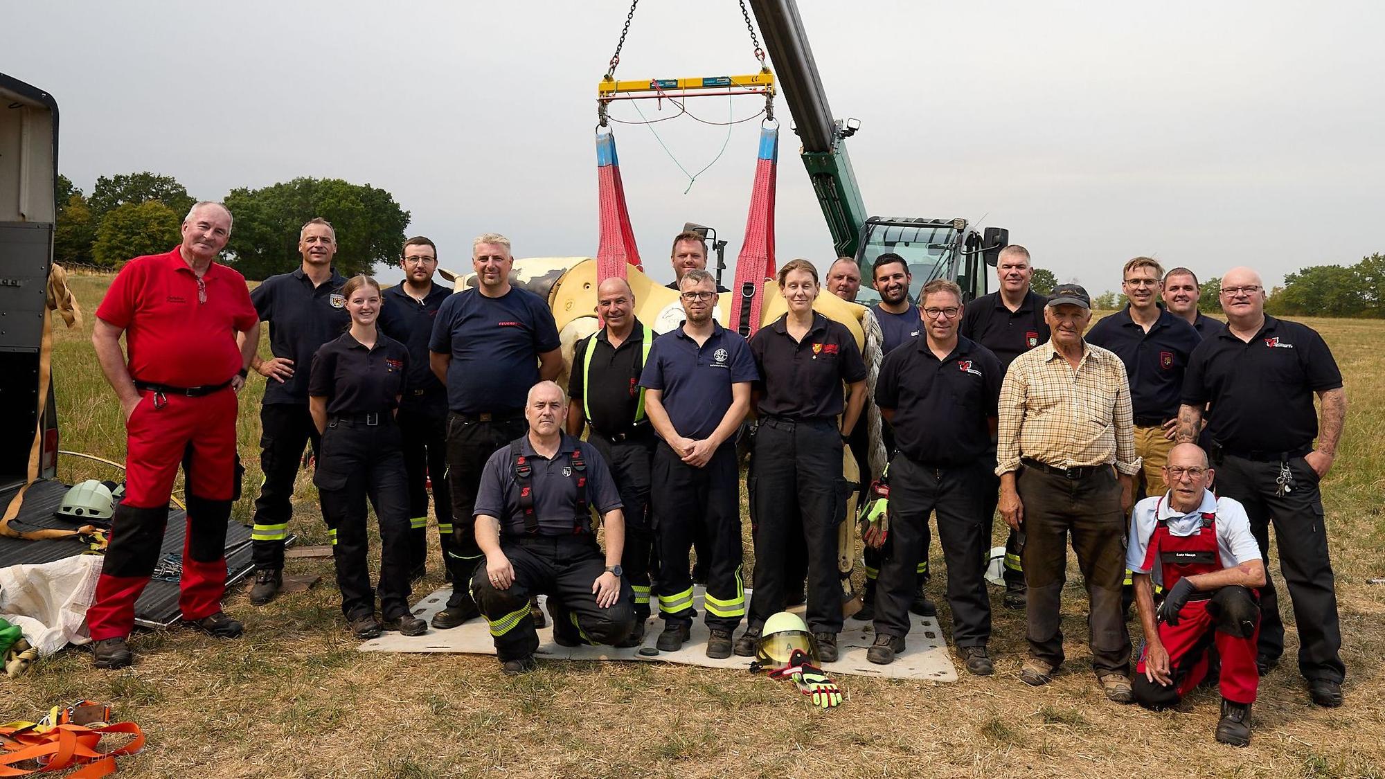 Feuerwehrleute stehen zu einem Gruppenbild mit hängendem Pferd zusammen.