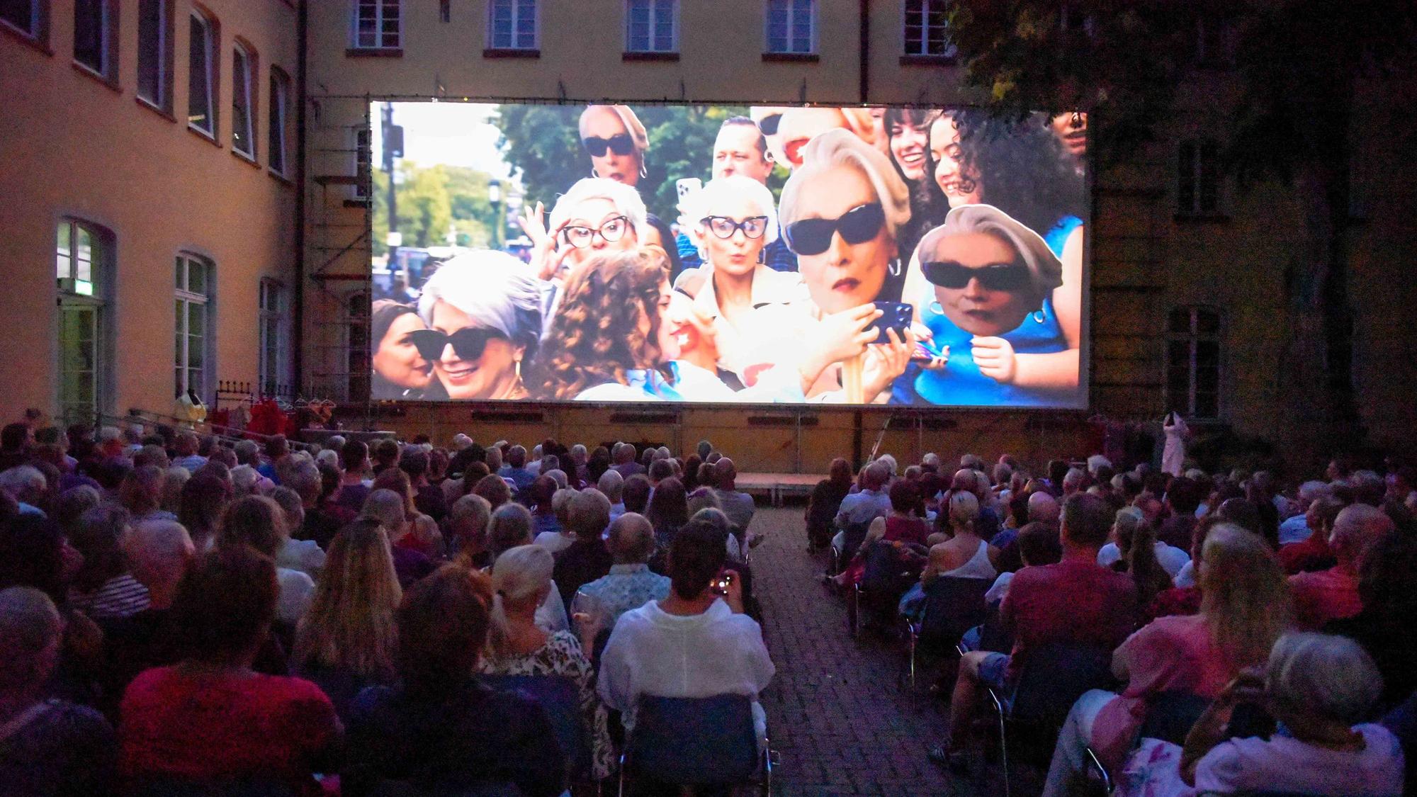 Rund 440 Zuschauer verfolgen unter freiem Himmel einen Film auf einer großen Leinwand.