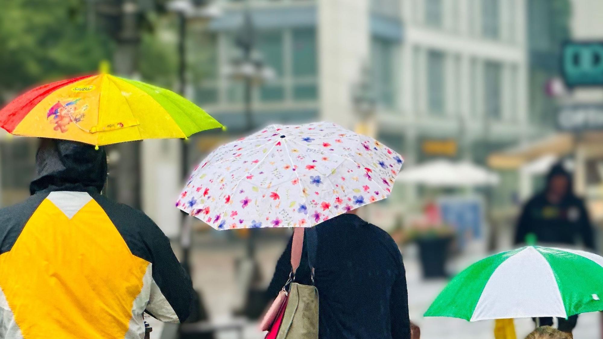 Menschen mit Regenschirmen gehen durch die Innenstadt von Brühl.