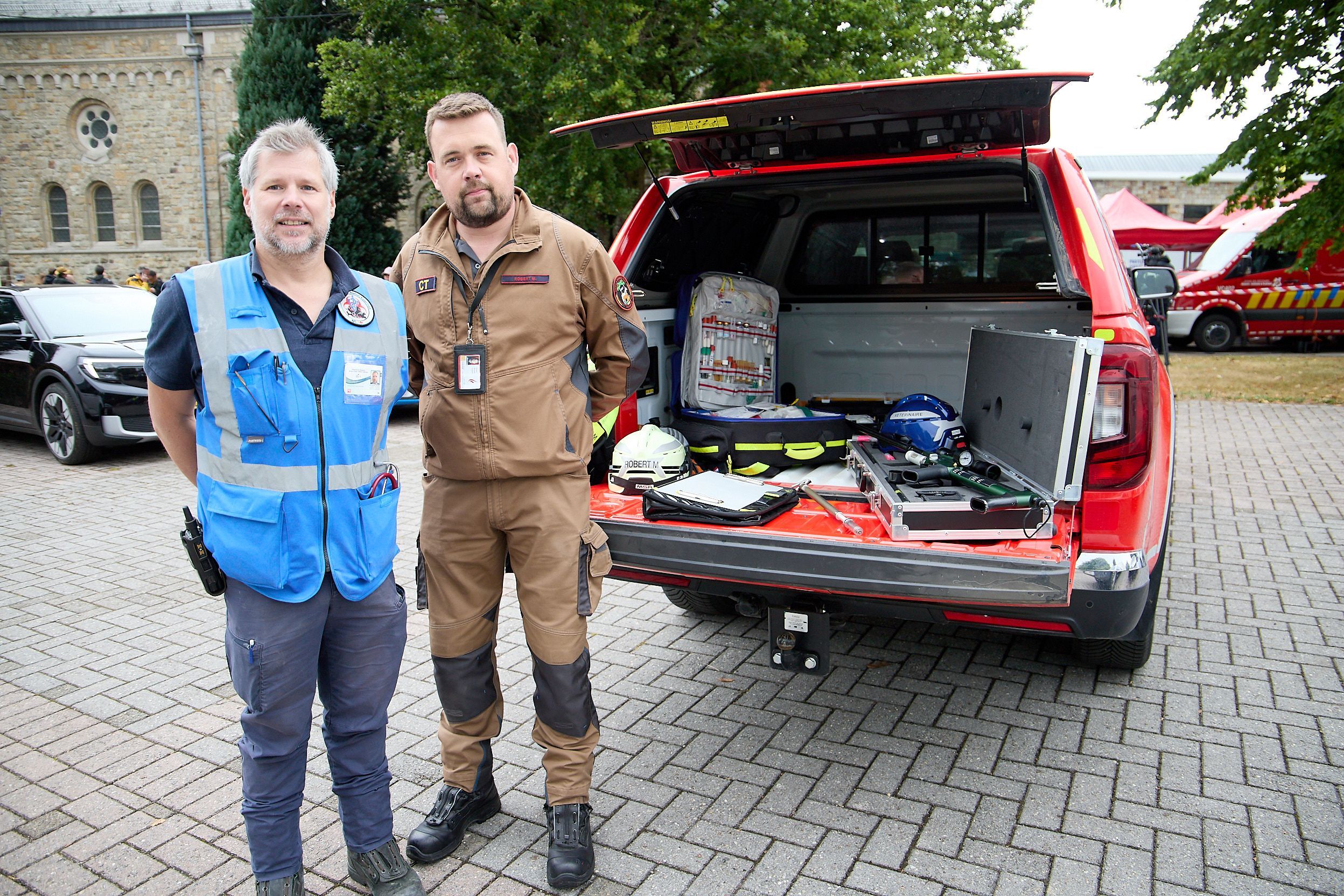 Zwei Mitarbeiter der Tierrettung der belgischen Feuerwehr stehen am geöffneten Kofferraum ihres Fahrzeugs.