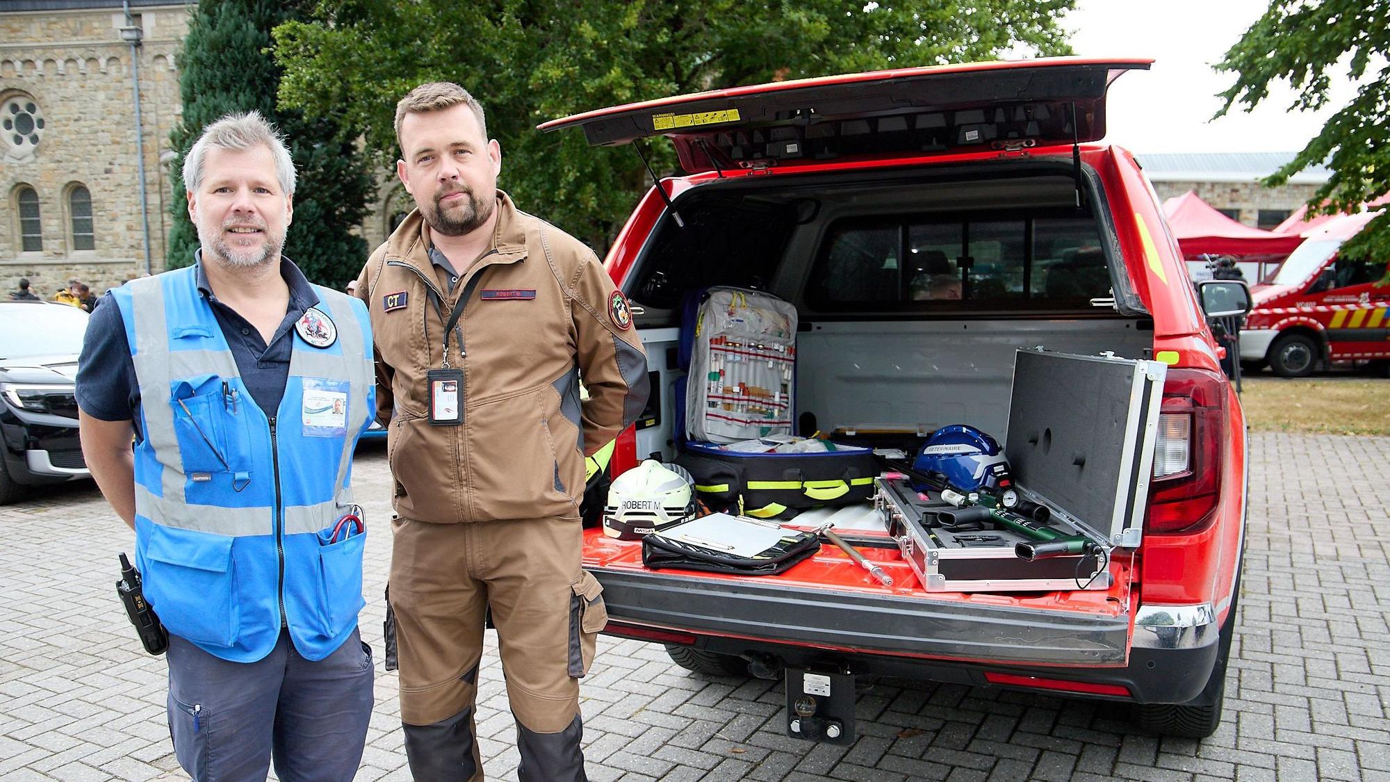 Zwei Mitarbeiter der Tierrettung der belgischen Feuerwehr stehen am geöffneten Kofferraum ihres Fahrzeugs.