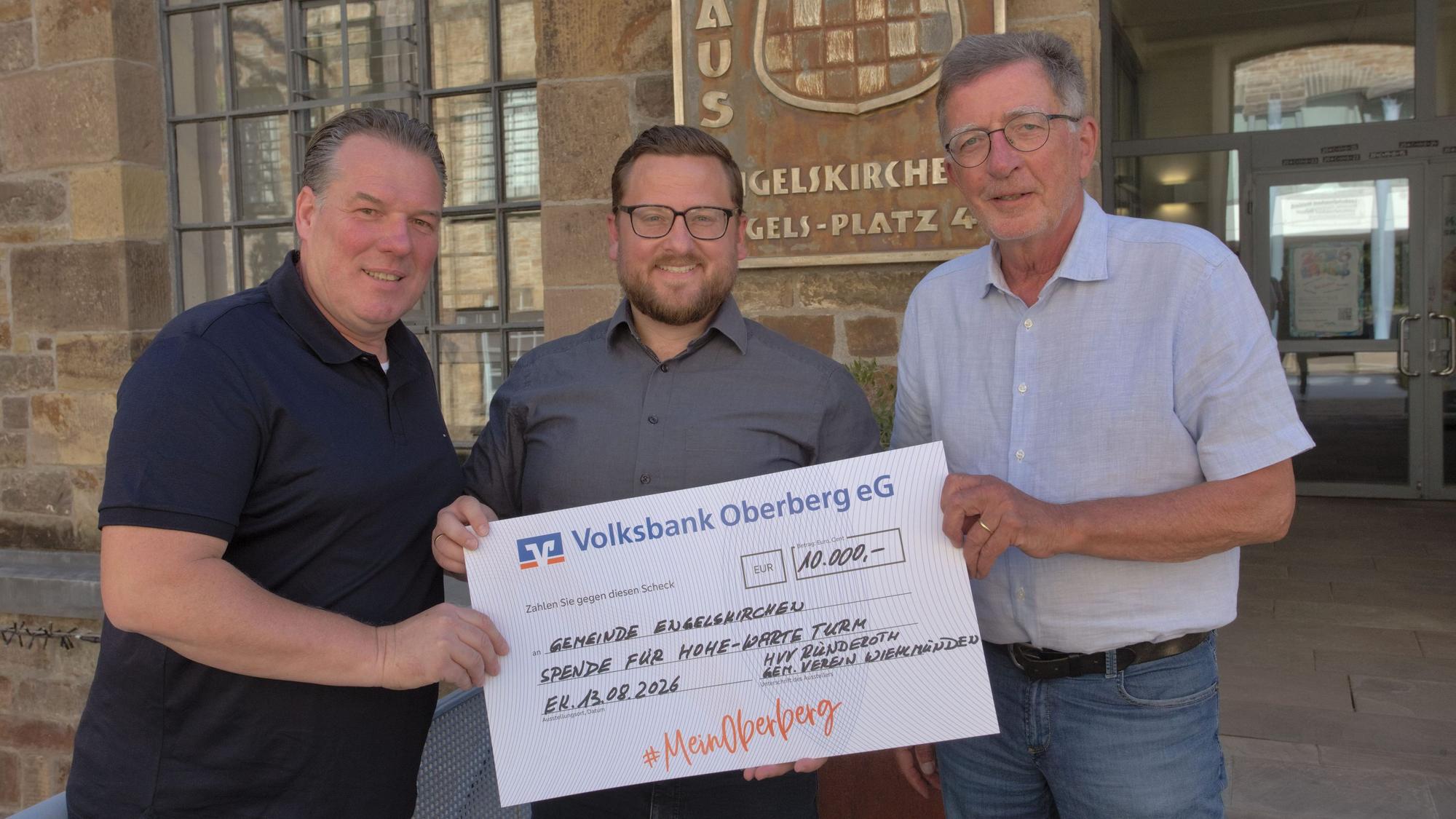 Drei Männer bei einer Scheckübergabe.