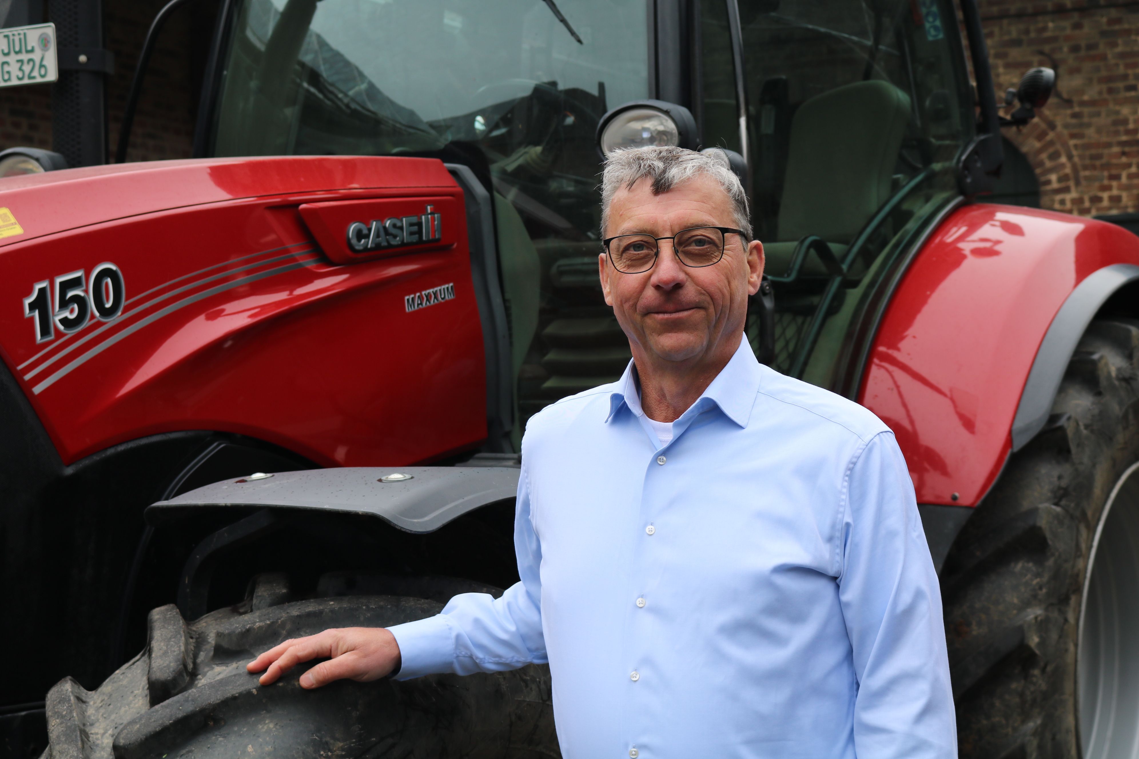 Porträt von Erich Gussen, Präsident des Rheinischen Landwirtschafts-Verbandes (RLV) vor einem Traktor