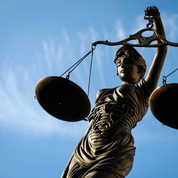Eine Statue der Justitia hält eine Waage in der Hand.