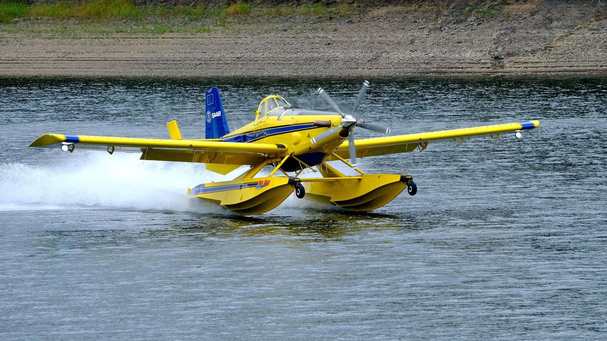 Ein gelb-blau lackiertes schwedisches Löschflugzeug wassert auf der Oleftalsperre in Hellenthal.