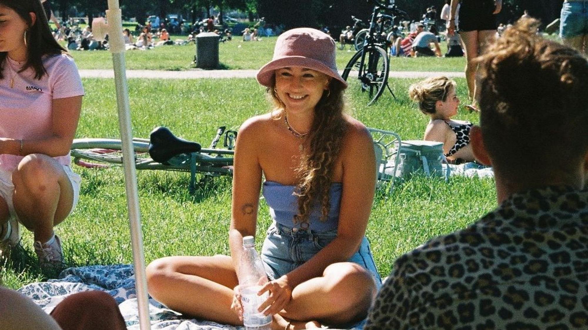 Eine Frau sitzt lachend auf einer Picknick-Decke.