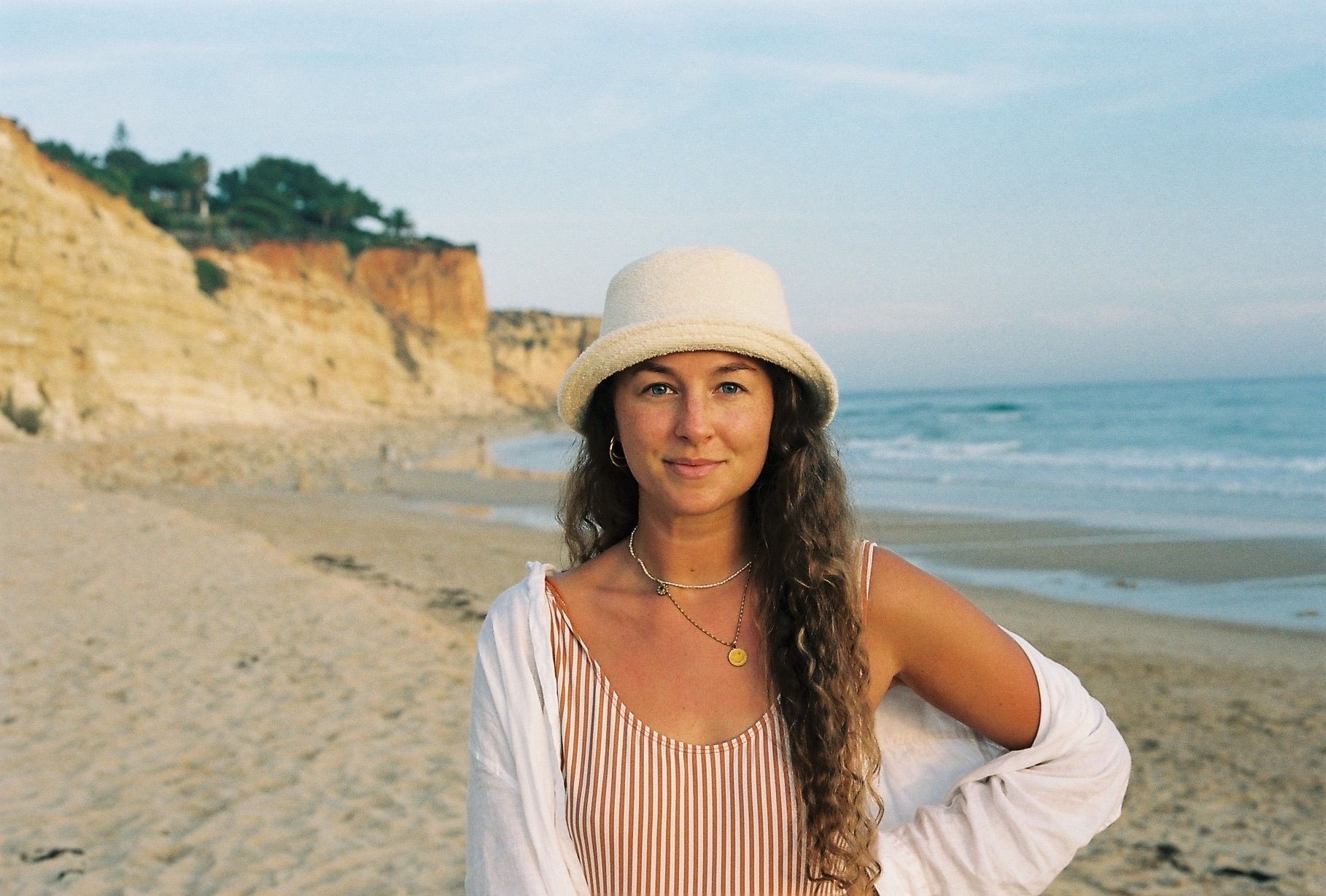 Eine Frau steht am Strand und lächelt in die Kamera.