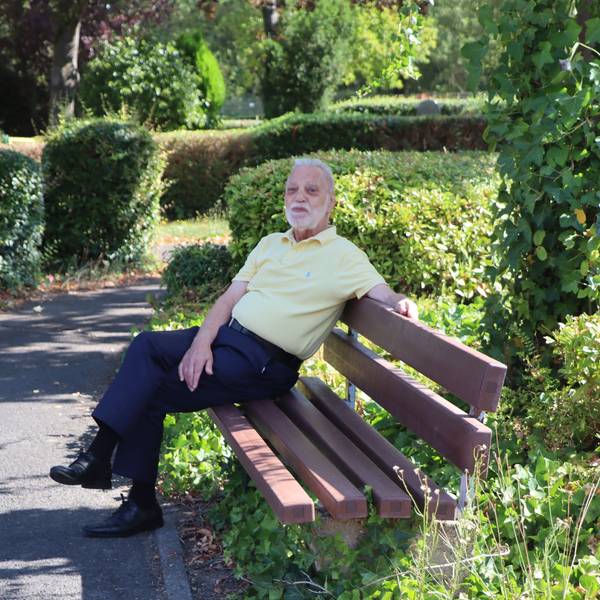 Ein Mann sitzt auf einer Bank auf einem Friedhof.