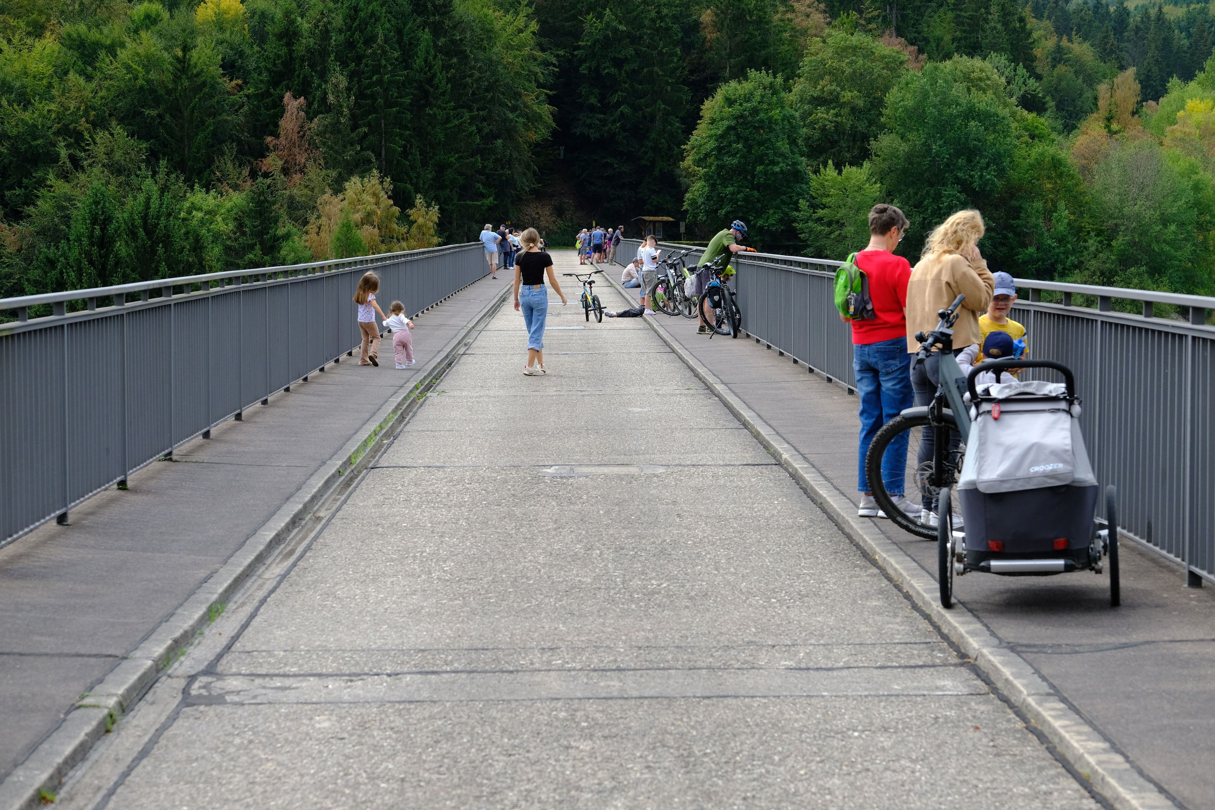Zahlreiche Schaulustige, darunter auch viele Kinder, halten sich auf der Dammkrone der Oleftalsperre Hellenthal auf.