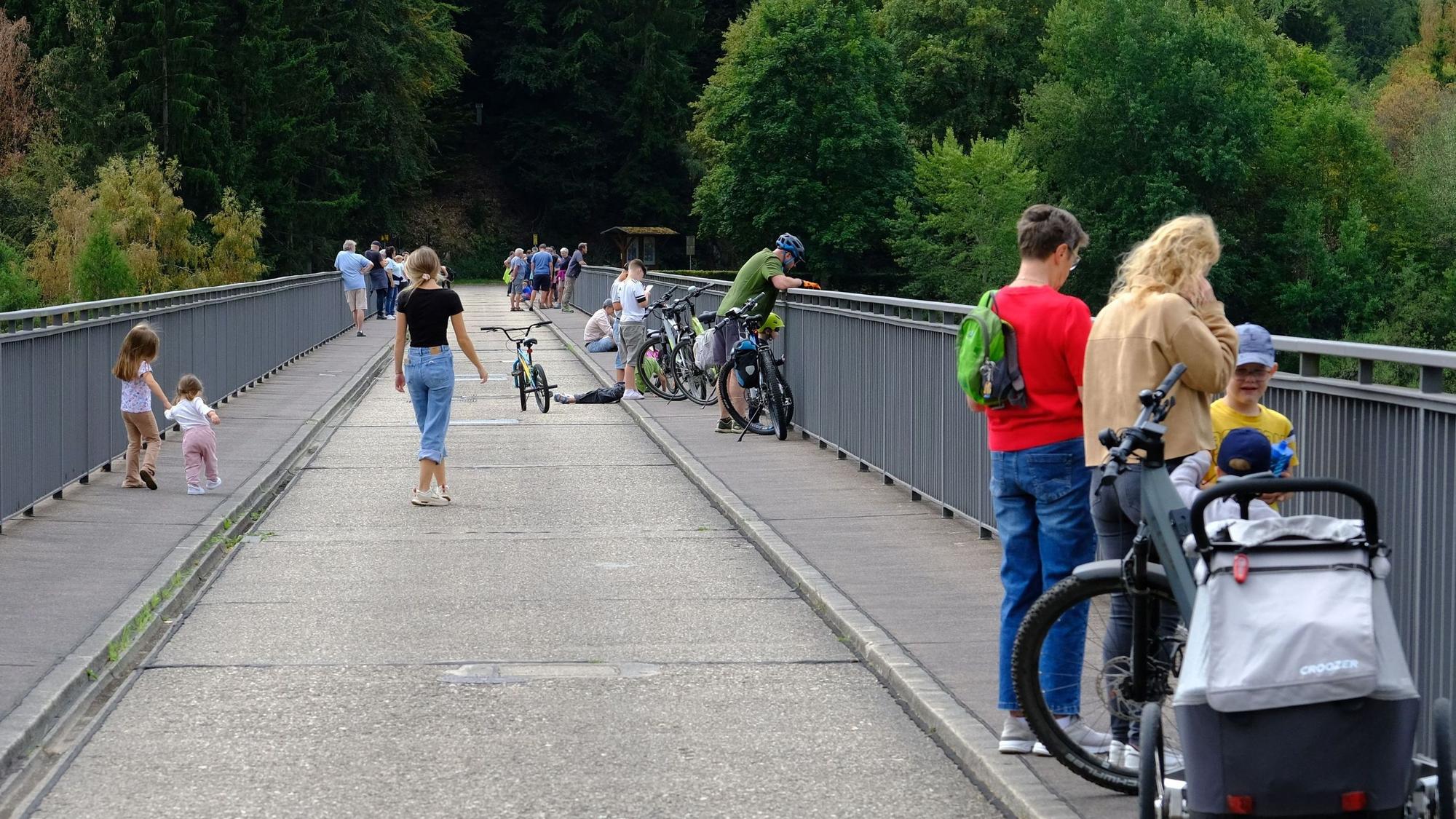 Zahlreiche Schaulustige, darunter auch viele Kinder, halten sich auf der Dammkrone der Oleftalsperre Hellenthal auf.