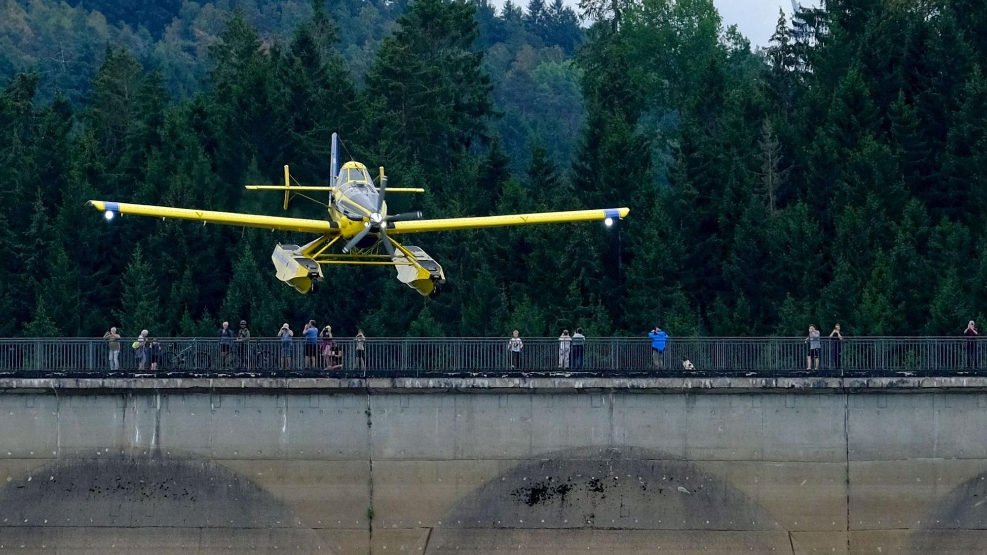 Von der Dammkrone aus beobachten zahlreiche Schaulustige den Anflug eines gelben Löschflugzeugs an der Oleftalsperre.