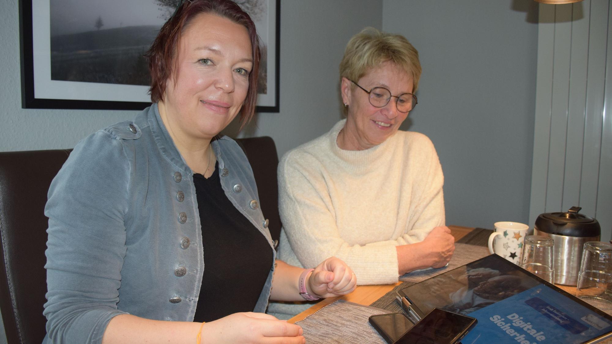 Zwei Frauen sitzen an einem Tisch, vor ihnen liegen ein Tablet und ein Smartphone.