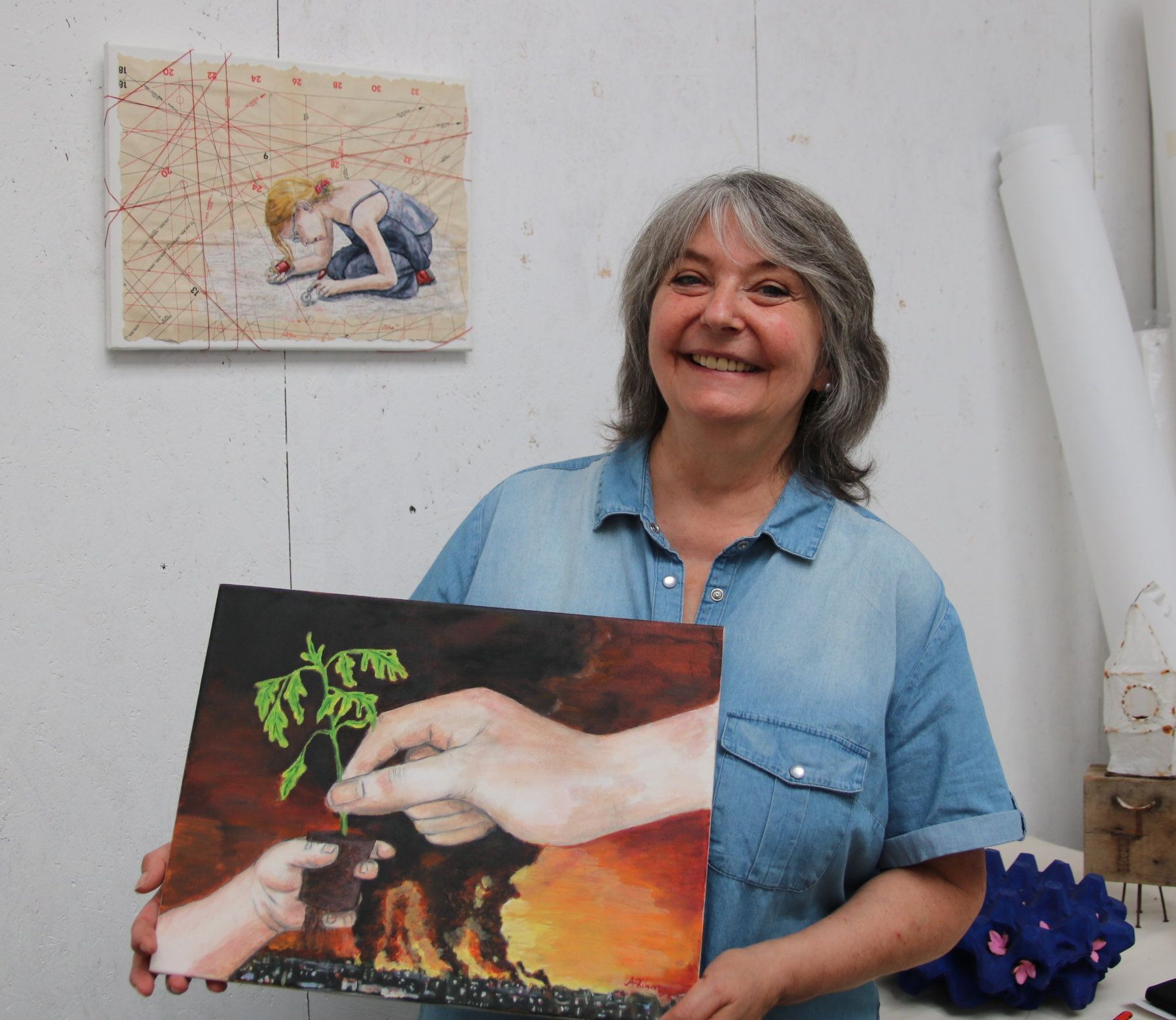 Eine Frau hält eines ihrer Kunstwerke in den Händen.