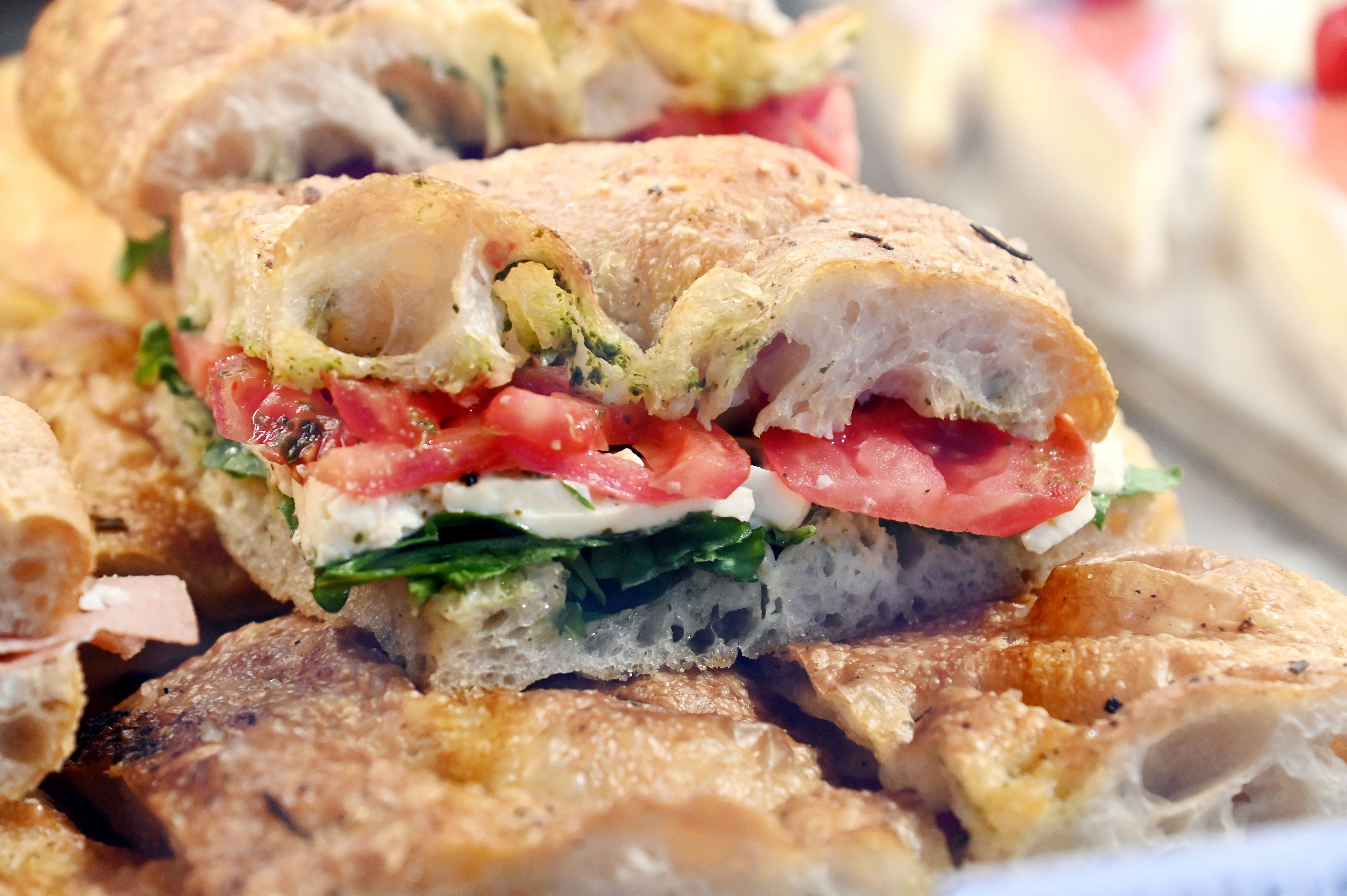 Ein Focaccia-Stück mit Tomaten, Mozzarella und Pesto liegt in der Auslage.