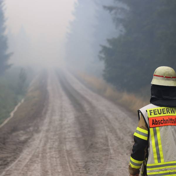 Ein Feuerwehrmann steht auf einem Weg in einem verqualmten Waldstück in der Nähe des Ortsteils Surbrot. Im belgischen Naturschutzgebiet Hohes Venn dauert der Kampf gegen die Flächenbrände an.