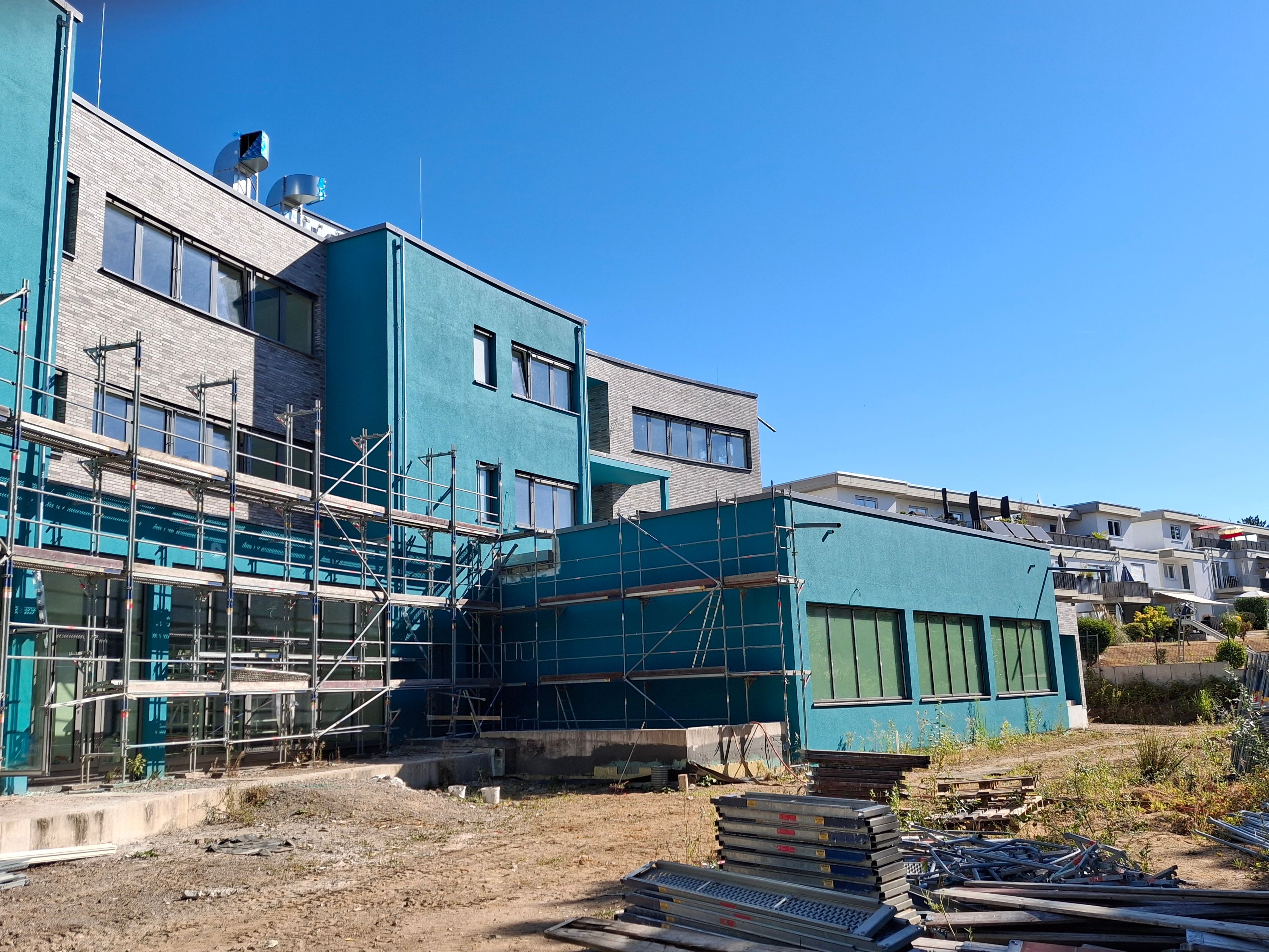 Die Baustelle besteht aus türkisen unfertigen Gebäuden, die eingezäunt sind.
