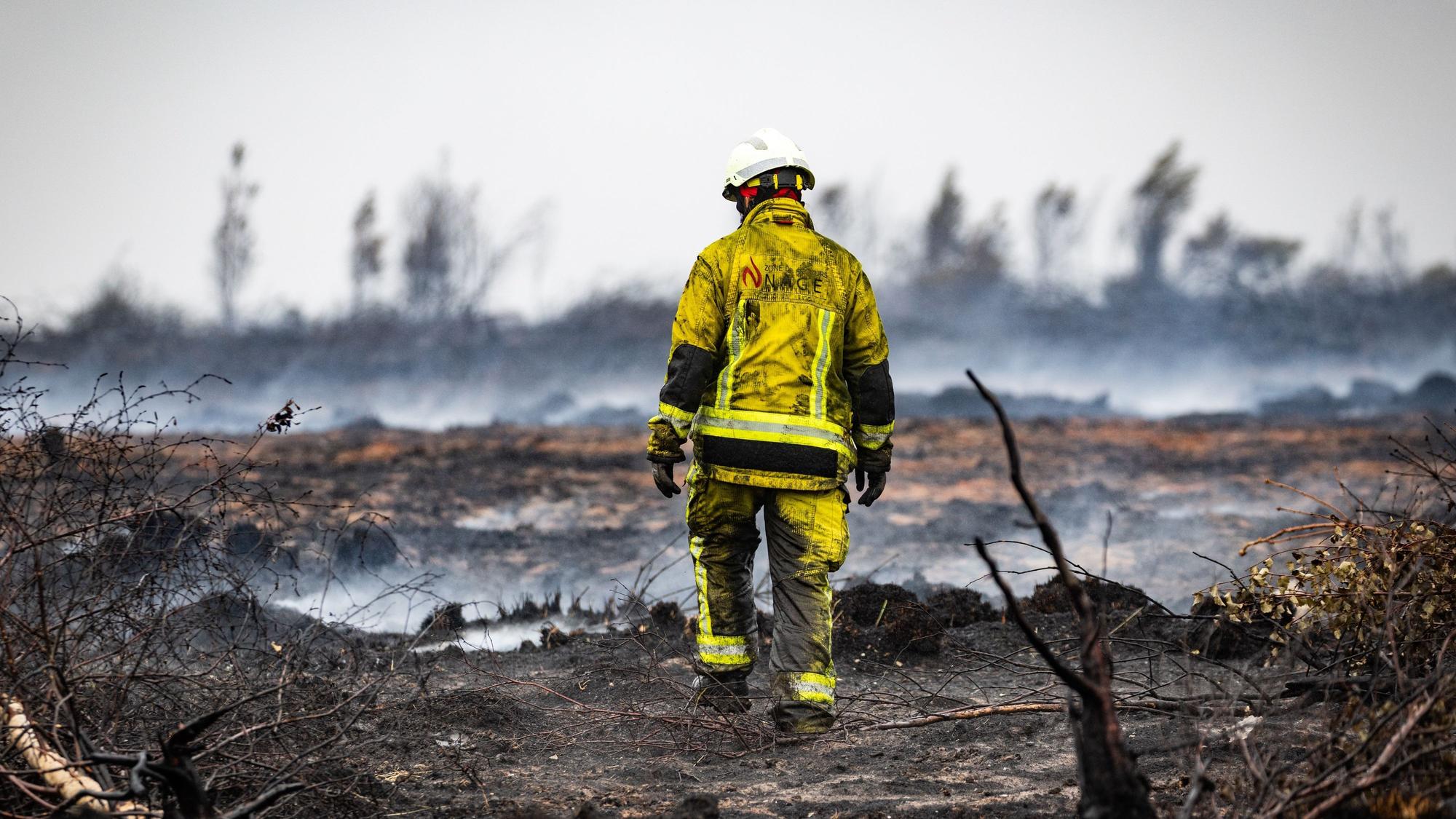 Das Foto zeigt einen Feuerwehrmann, der Glutnester löscht.