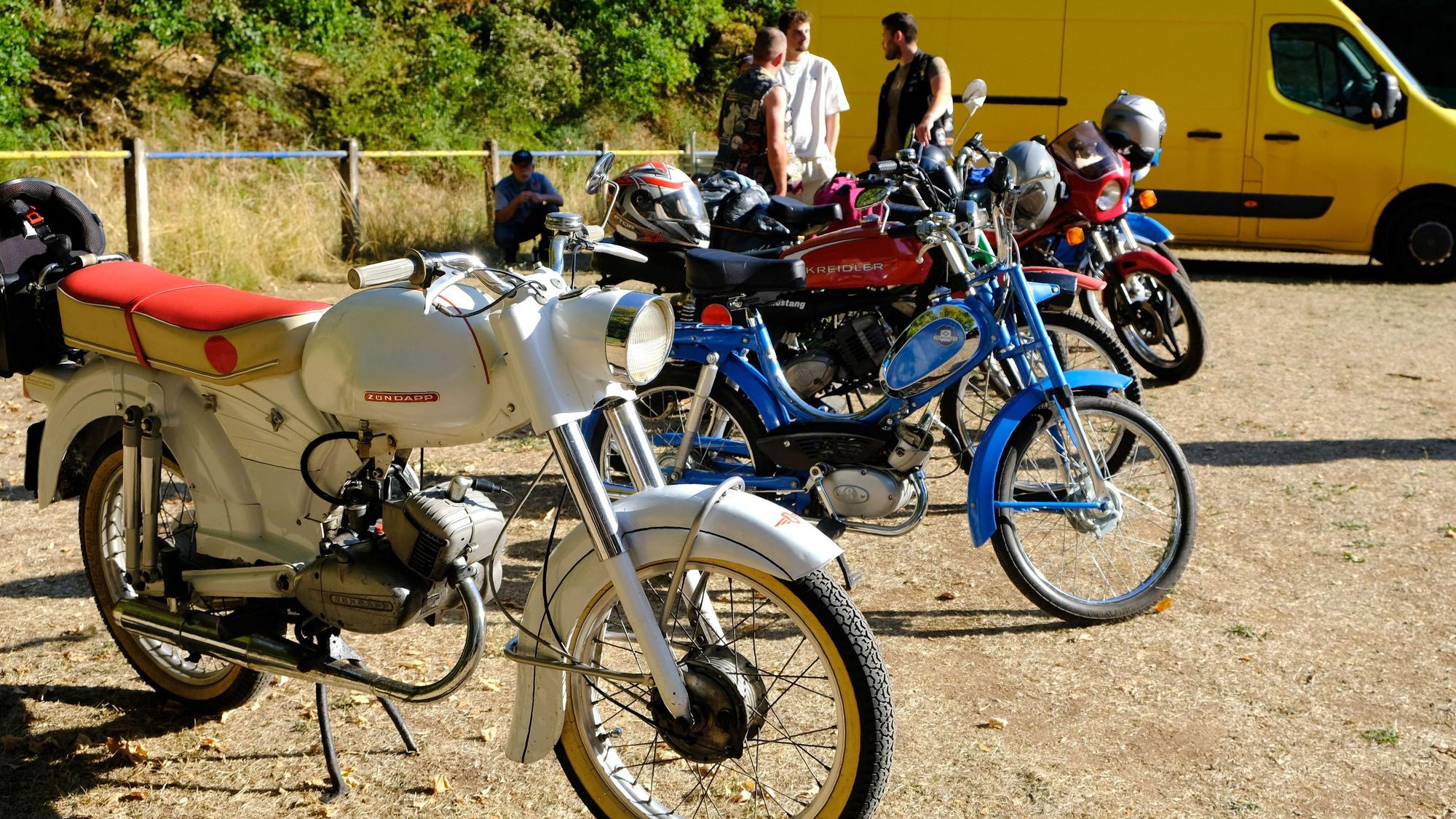 Auf dem Sportplatz in Vussem sind einige ältere Mopeds und Mofas in Reihe geparkt.