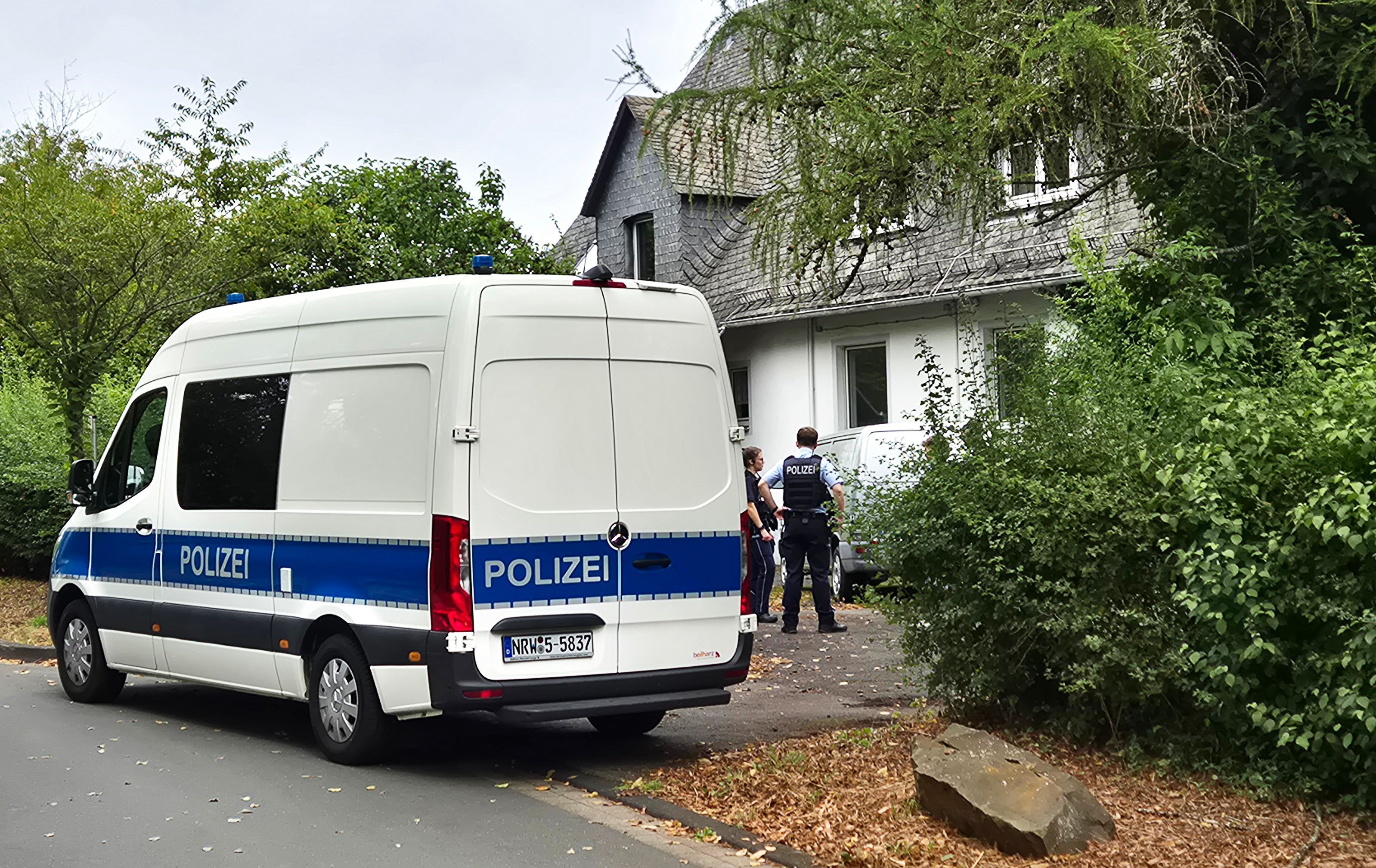 Einsatzkräfte der Polizei stehen vor einem Wohnhaus in Siegen. Dort wurden die Leichen entdeckt.
