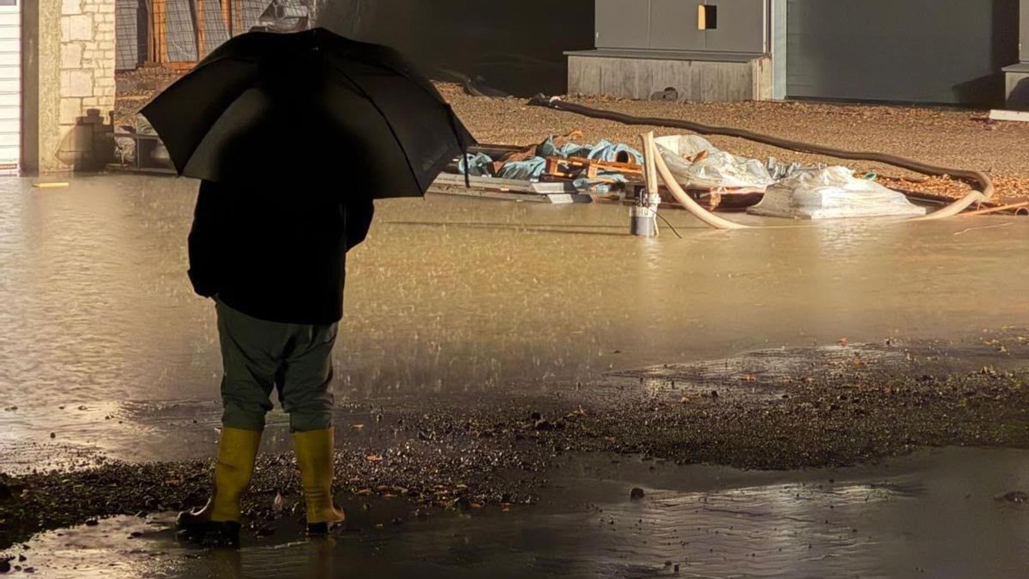 Auf dem Foto ist ein Mann mit Regenschirm zu sehen.