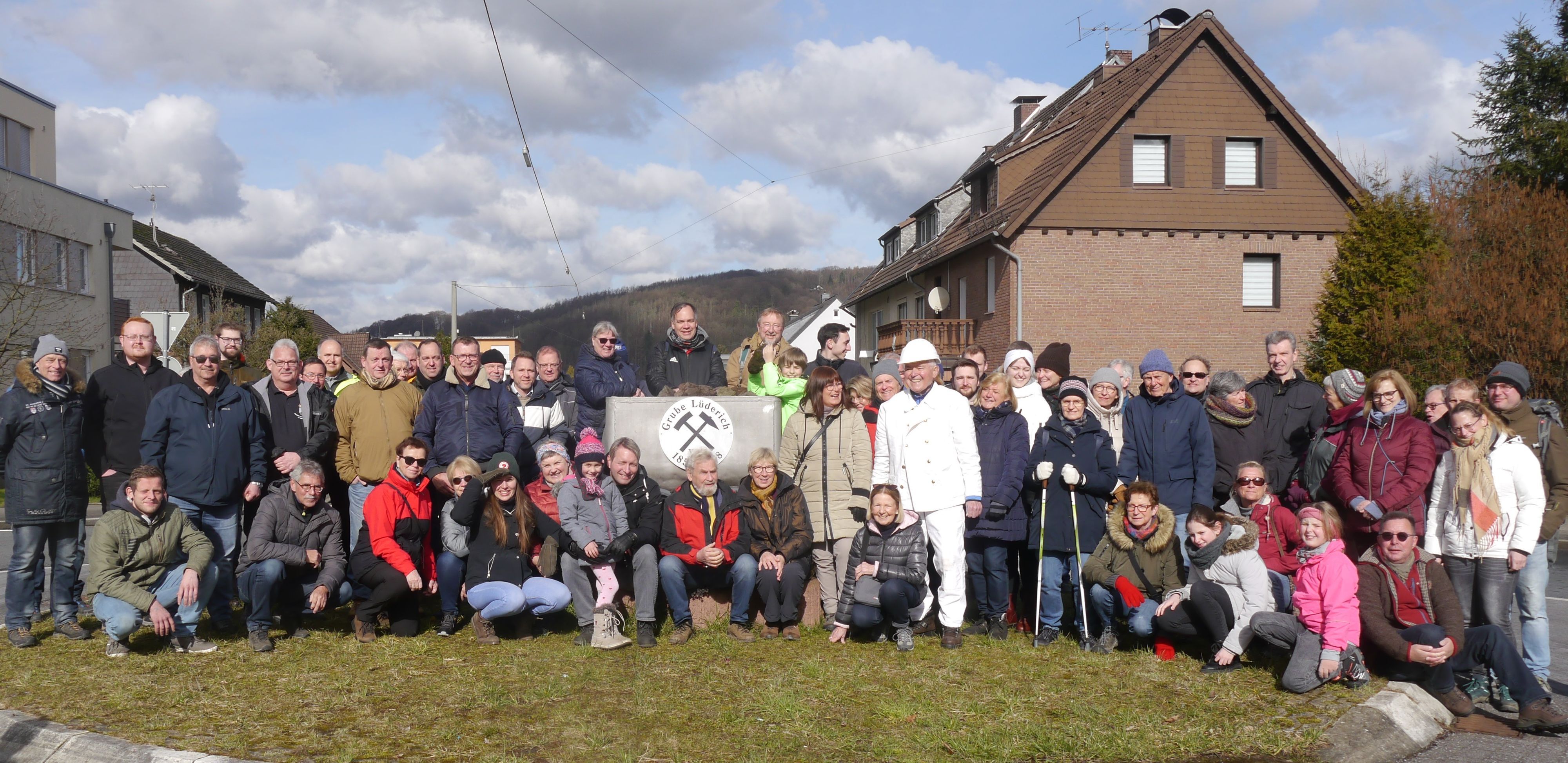 Zu sehen ist eine große Gruppe im Winter, die an einem Bergbau-Symbol steht.