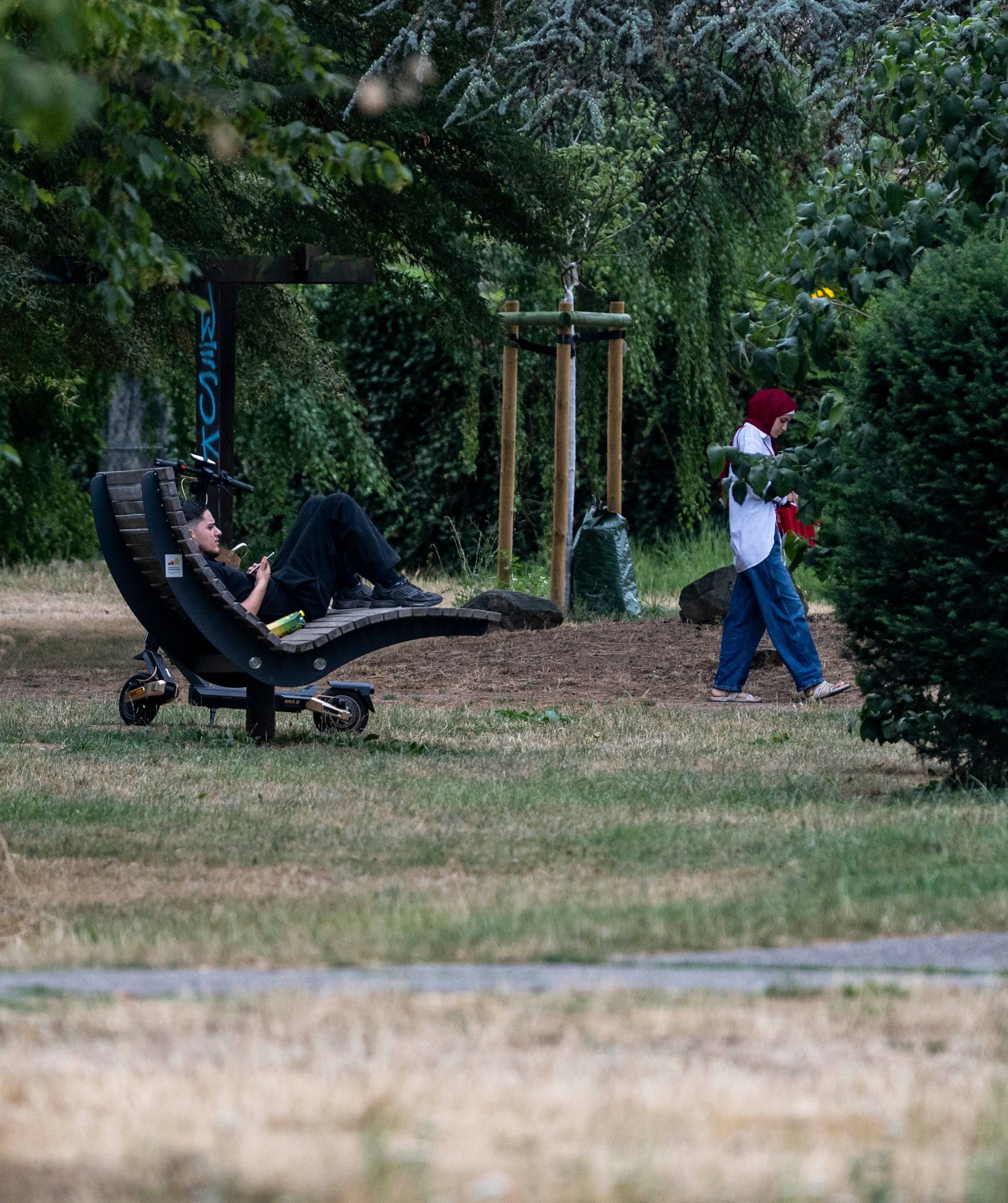 Ein junger Mann sitzt auf einer Holzliege.