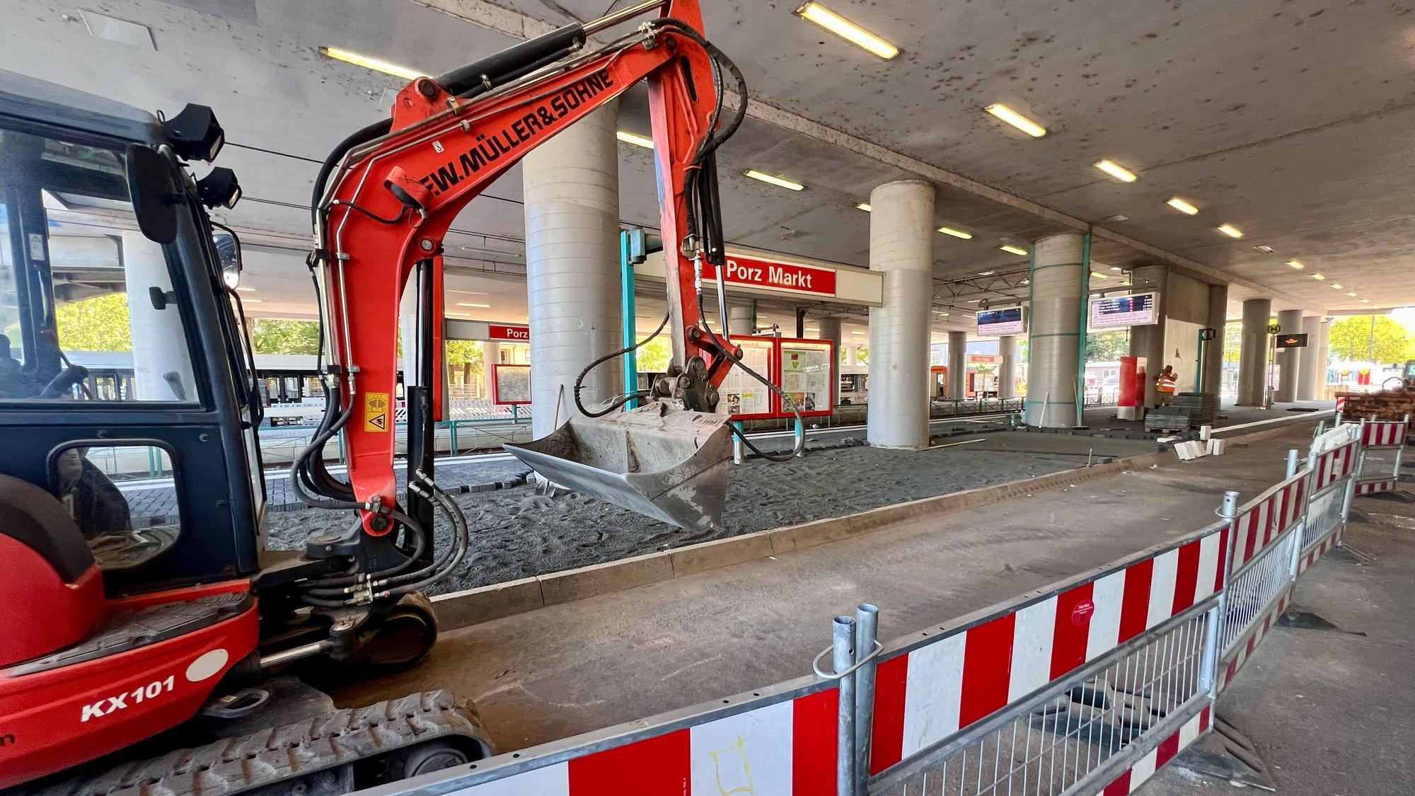 Ein Bagger steht an der Haltestelle Porz Markt, drumherum rot-weiße Absperrgitter.