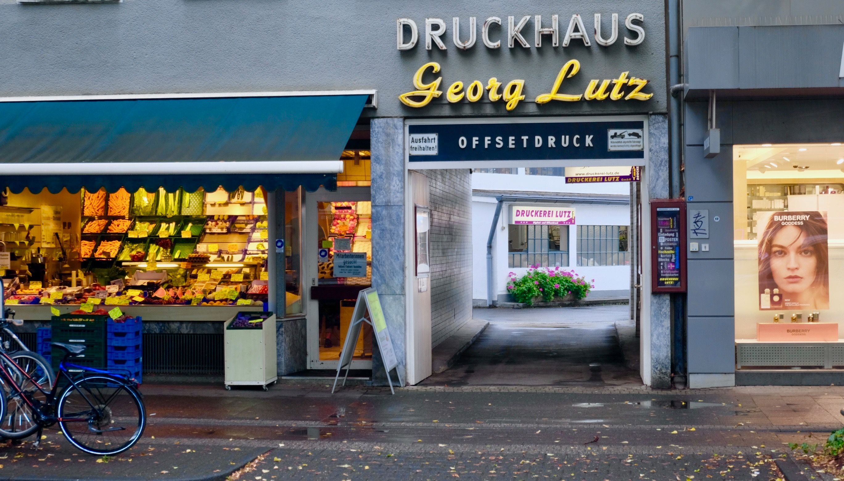 Neben einem Gemüseladen liegt die Einfahrt zum Druckhaus Georg Lutz.