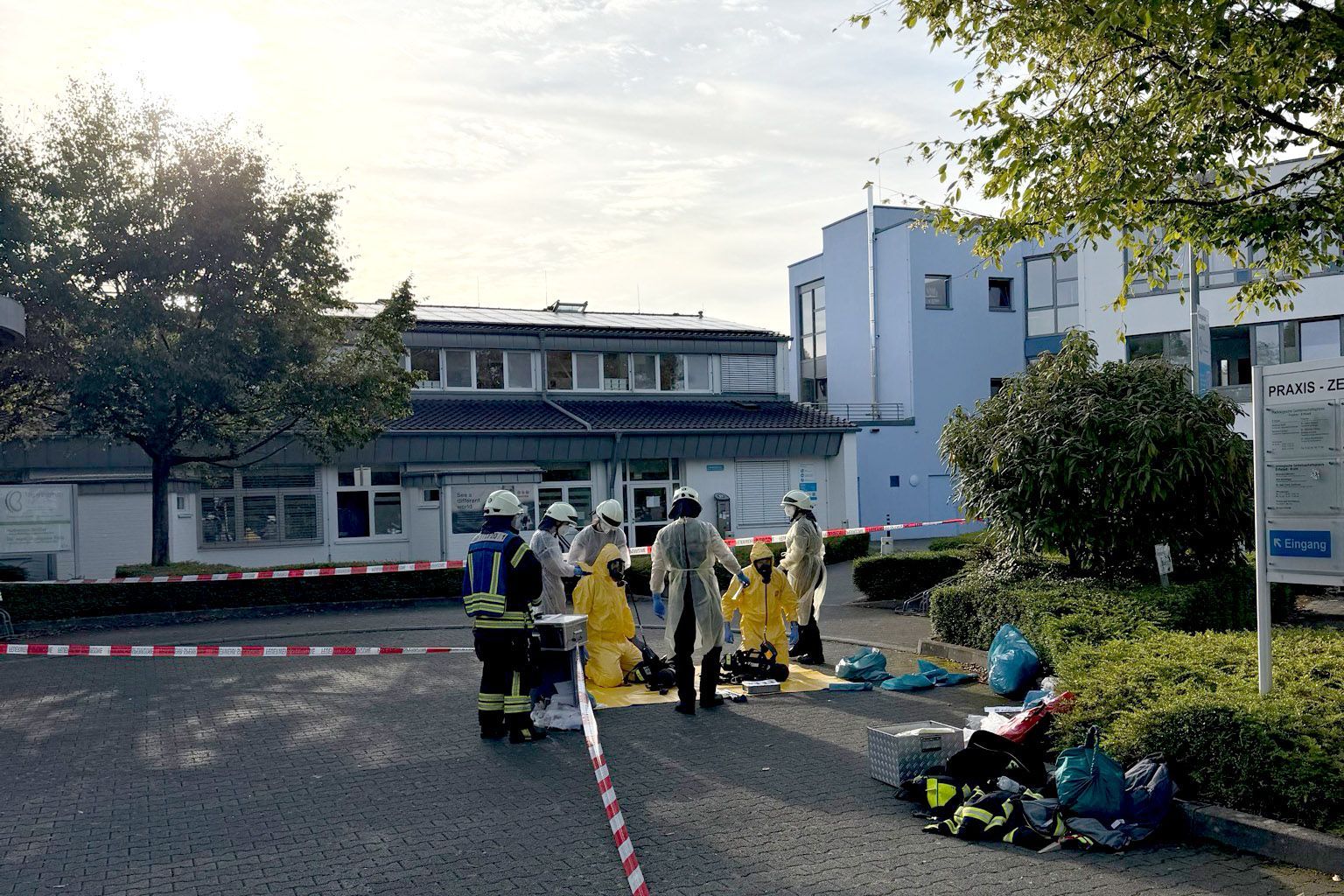 Vor einem Krankenhaus stehen Feuerwehrleute, zum Teil in Schutzanzügen.